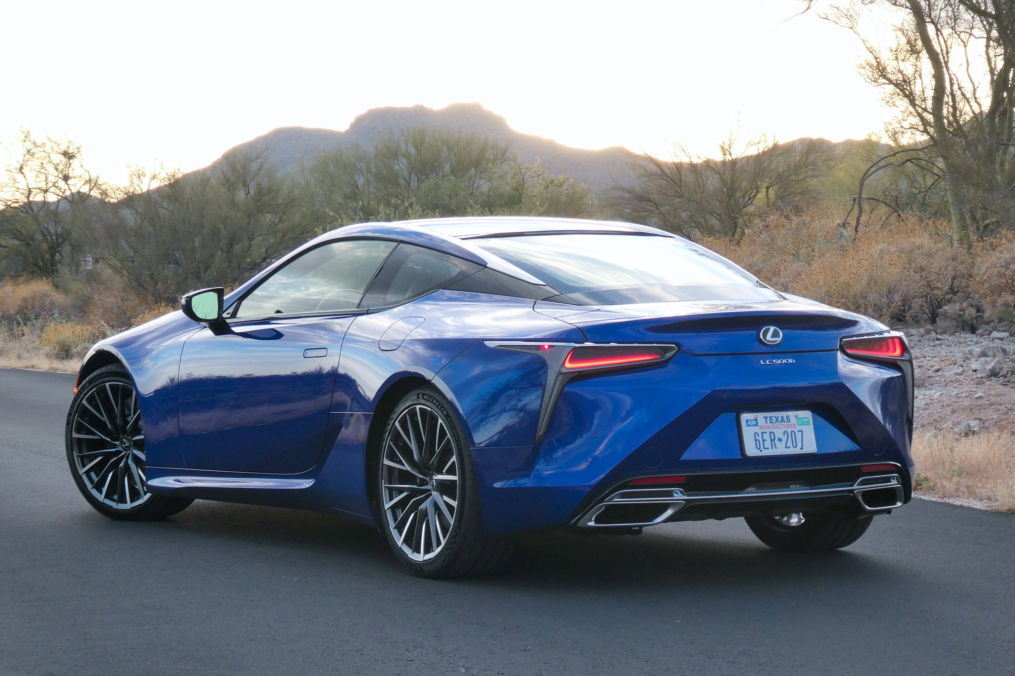 Rear-quarter of a blue 2024 Lexus LC 500h with desert and mountains in the background