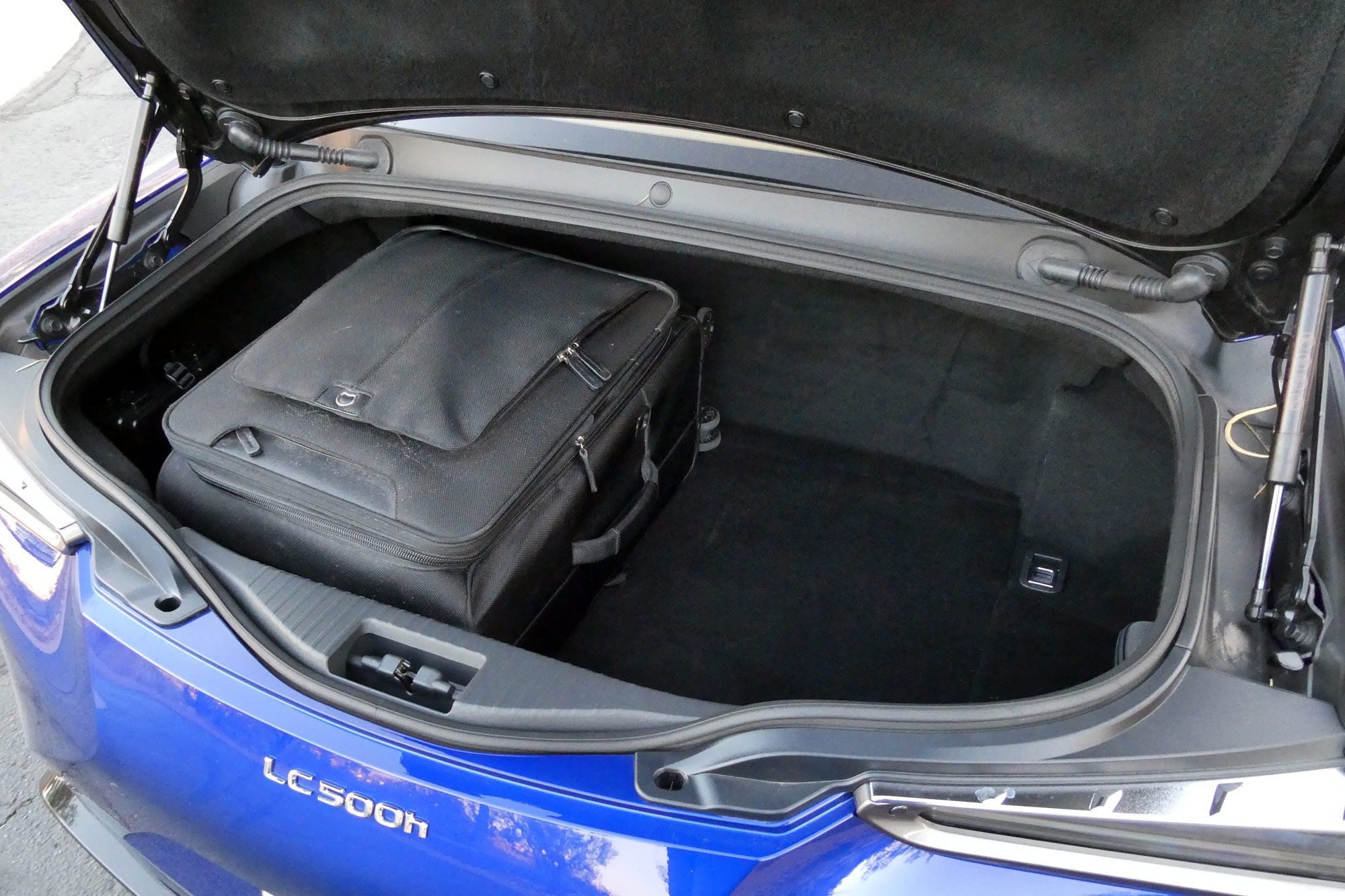 2024 Lexus LC 500h showing the trunk with a black roll-aboard suitcase inside