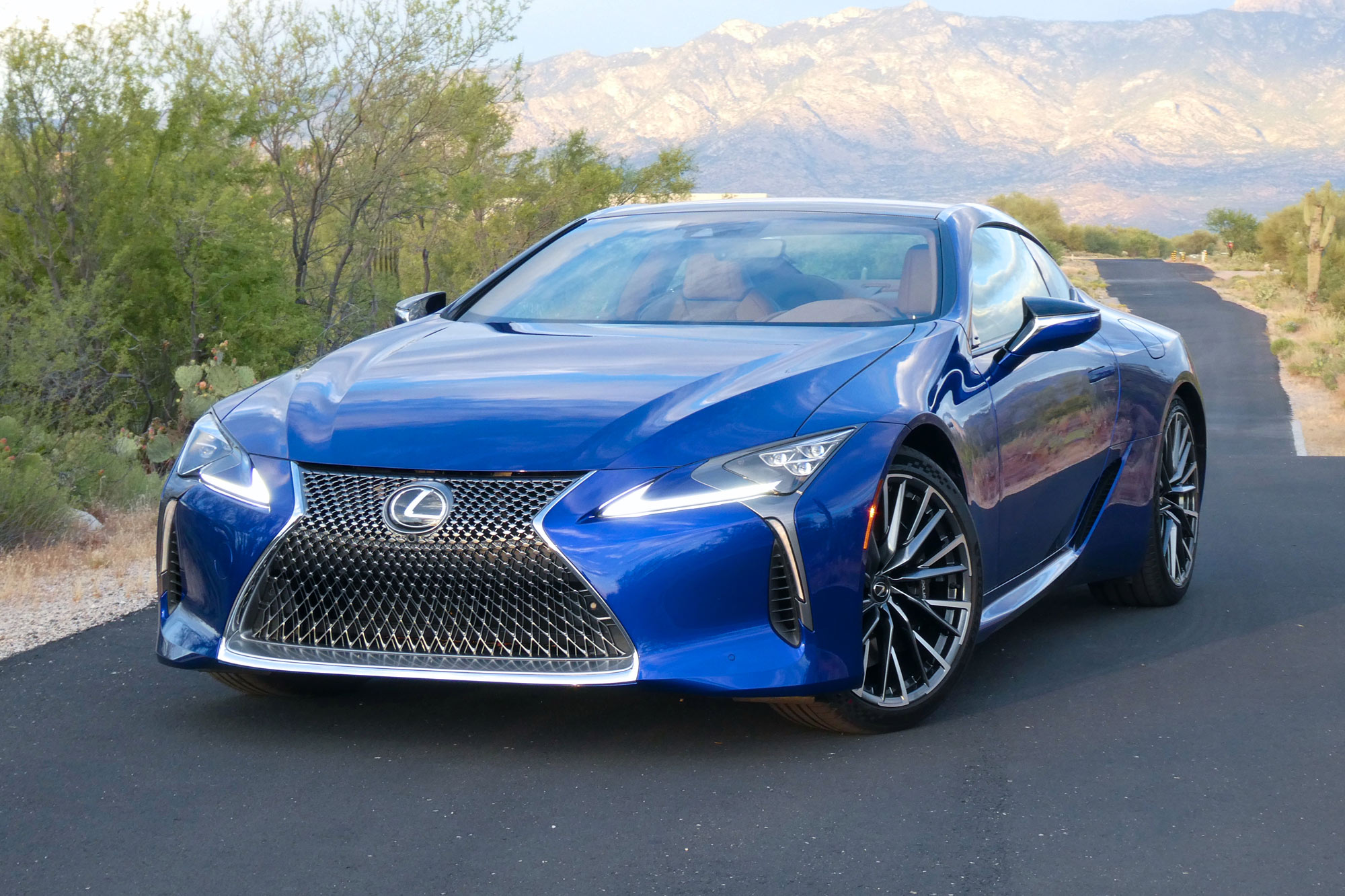 Front-quarter of a blue 2024 Lexus LC 500h with desert and mountains in the background