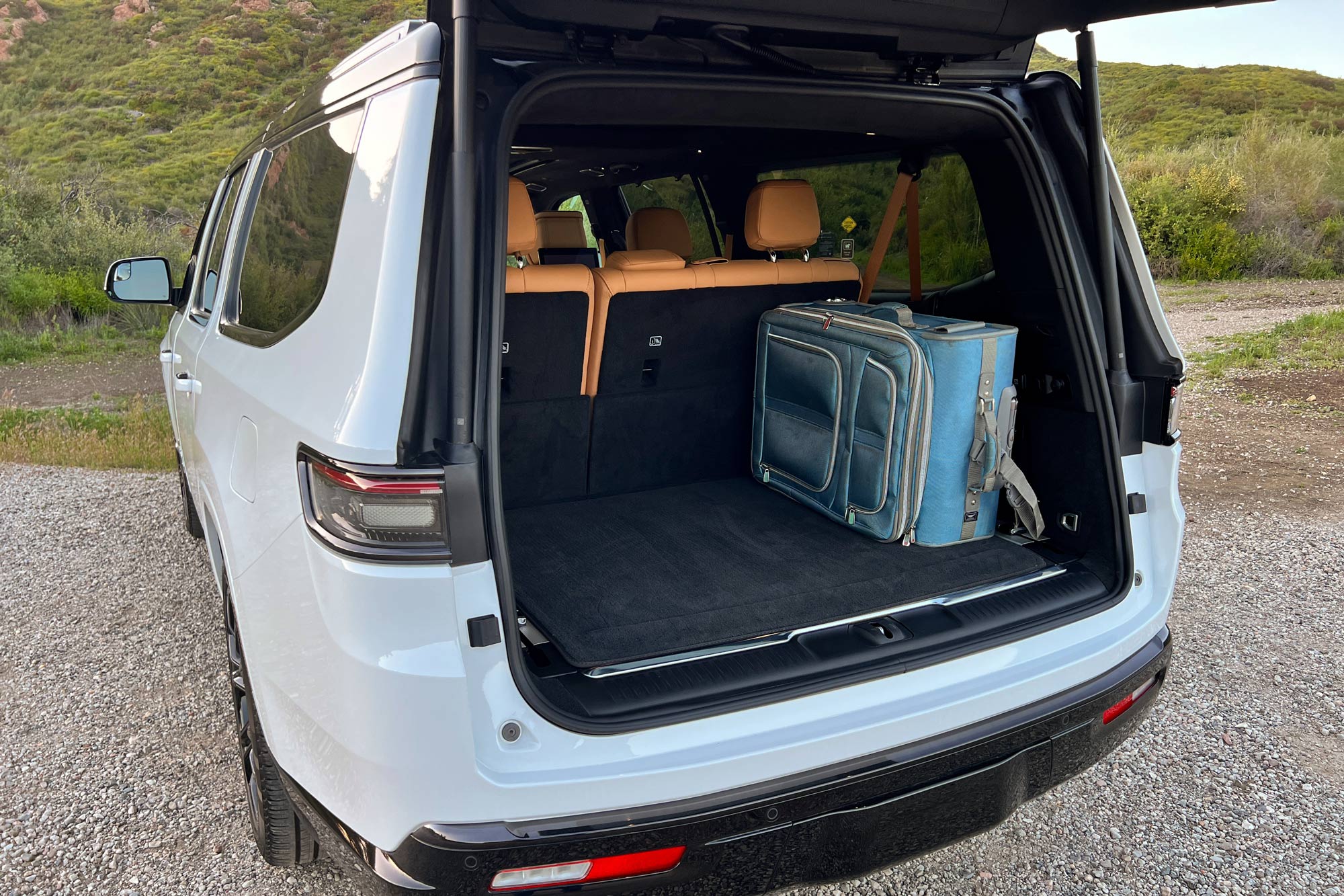 Cargo space in a 2024 Jeep Grand Wagoneer L Series III Obsidian, with a blue full-size suitcase