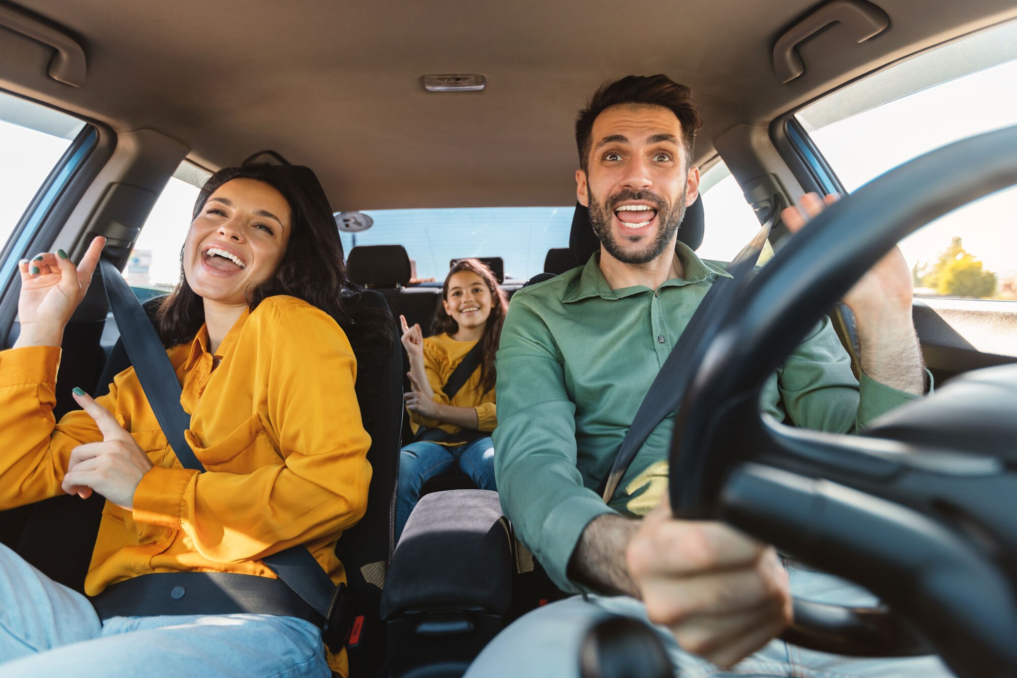 Happy family sings and laughs on road trip.