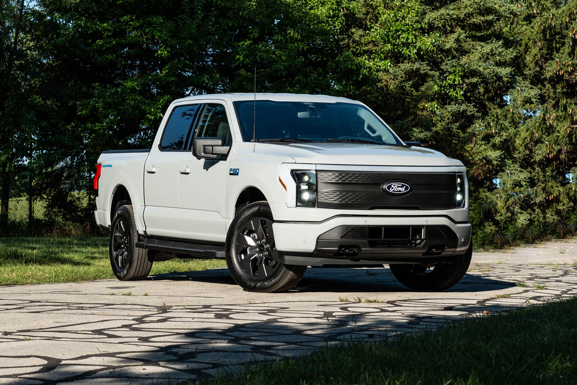 2024 Ford F-150 Lightning Flash in Avalanche White with trees in the background.