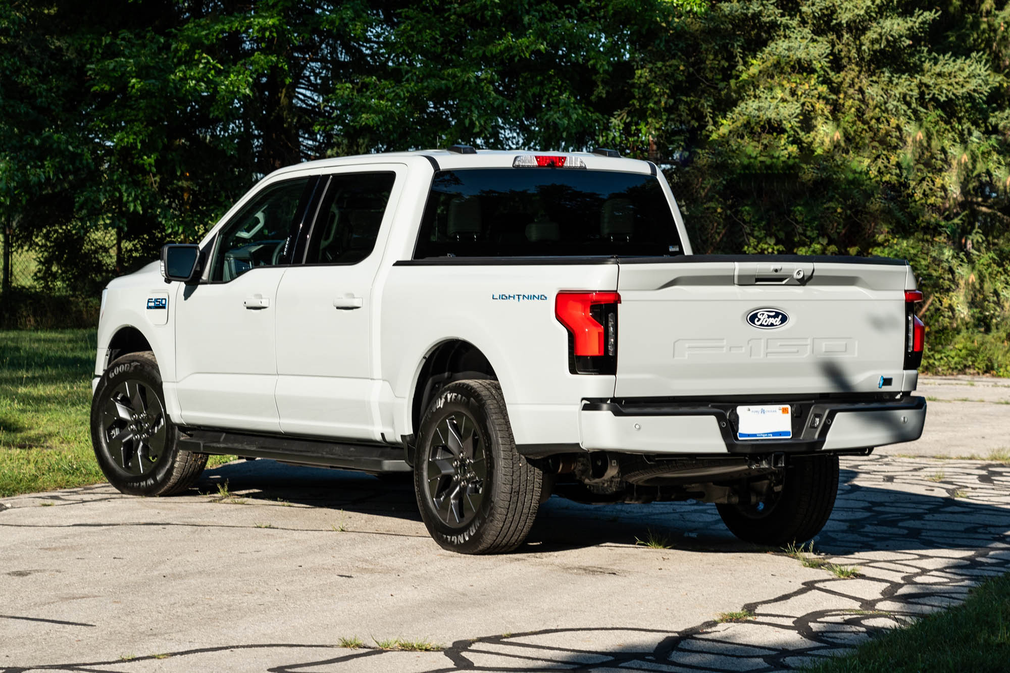 2024 Ford F-150 Lightning Flash in Avalanche White with trees in the background.