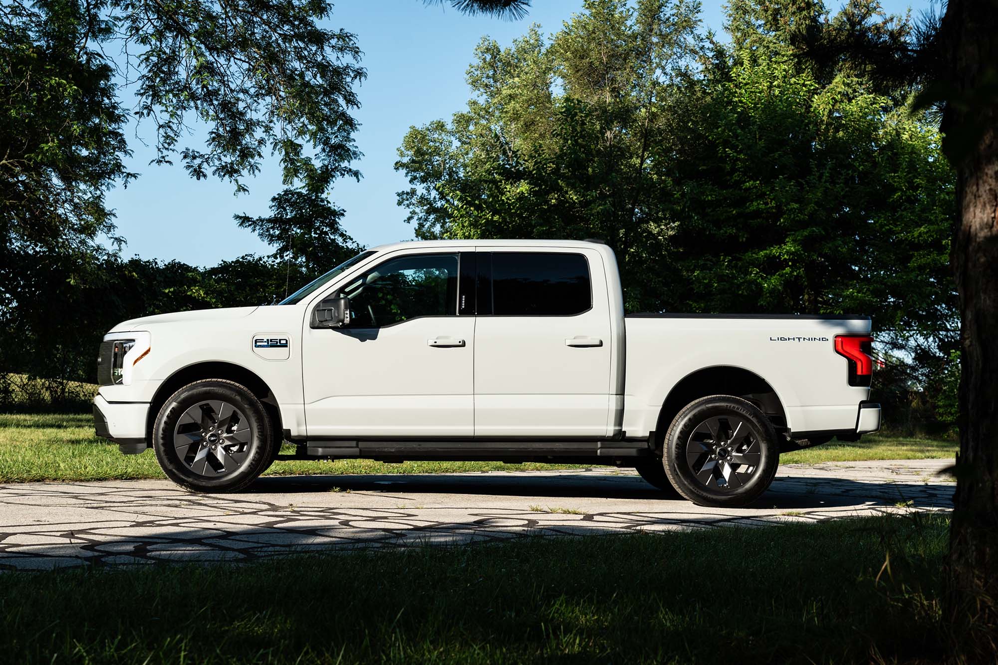 2024 Ford F-150 Lightning Flash in Avalanche White with trees in the background.