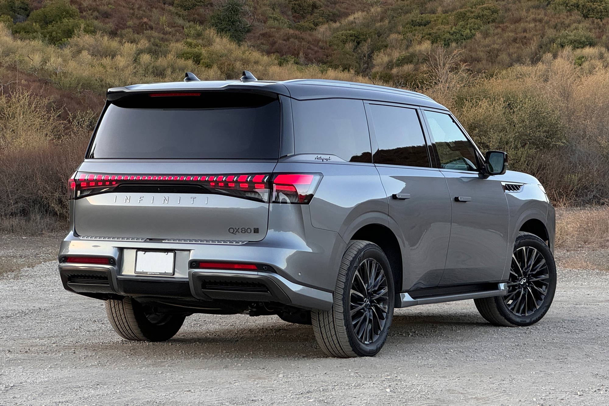 2025 Infiniti QX80 Autograph in Dynamic Metal with a brush-covered hillside in the background.