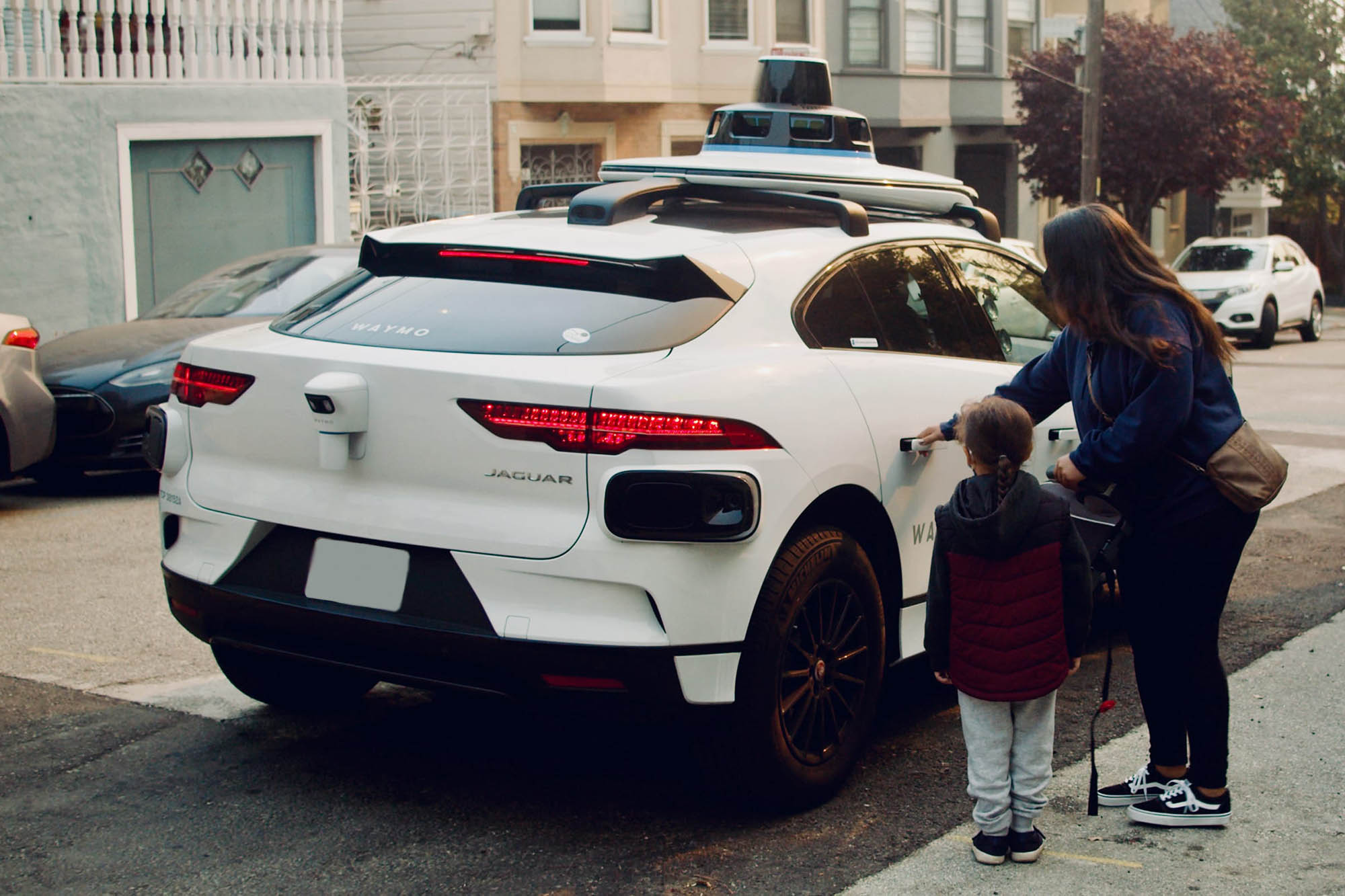 A person and child getting into a Waymo taxi