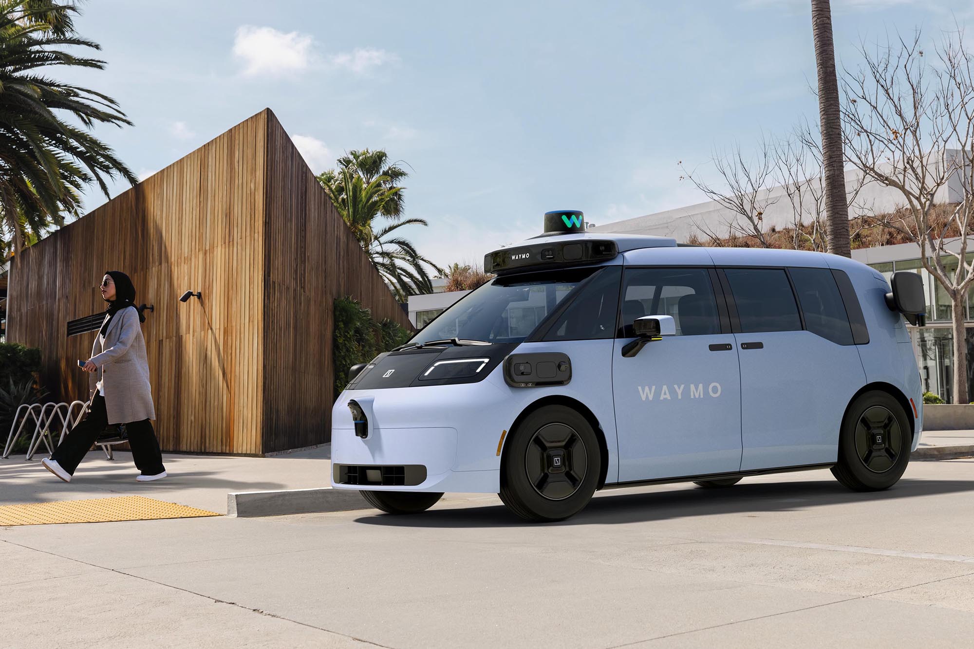 A sixth-generation Waymo autonomous taxi sitting a a curb