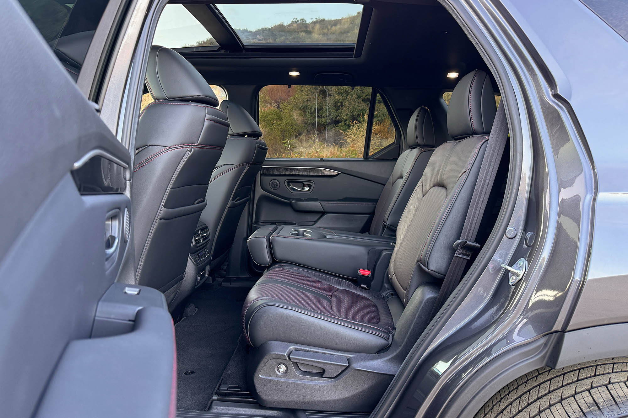 2025 Honda Pilot Black Edition interior showing the second-row seats and panoramic sunroof.