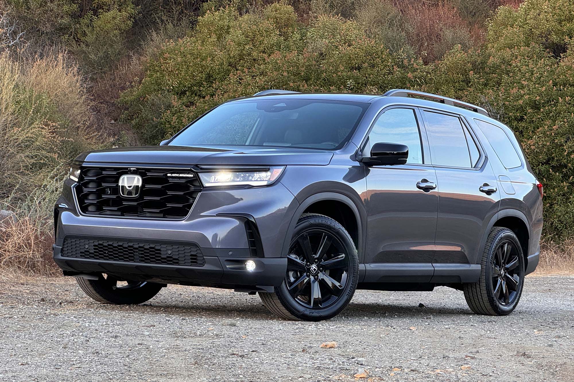 2025 Honda Pilot Black Edition in Modern Steel with a brush-covered hill in the background.