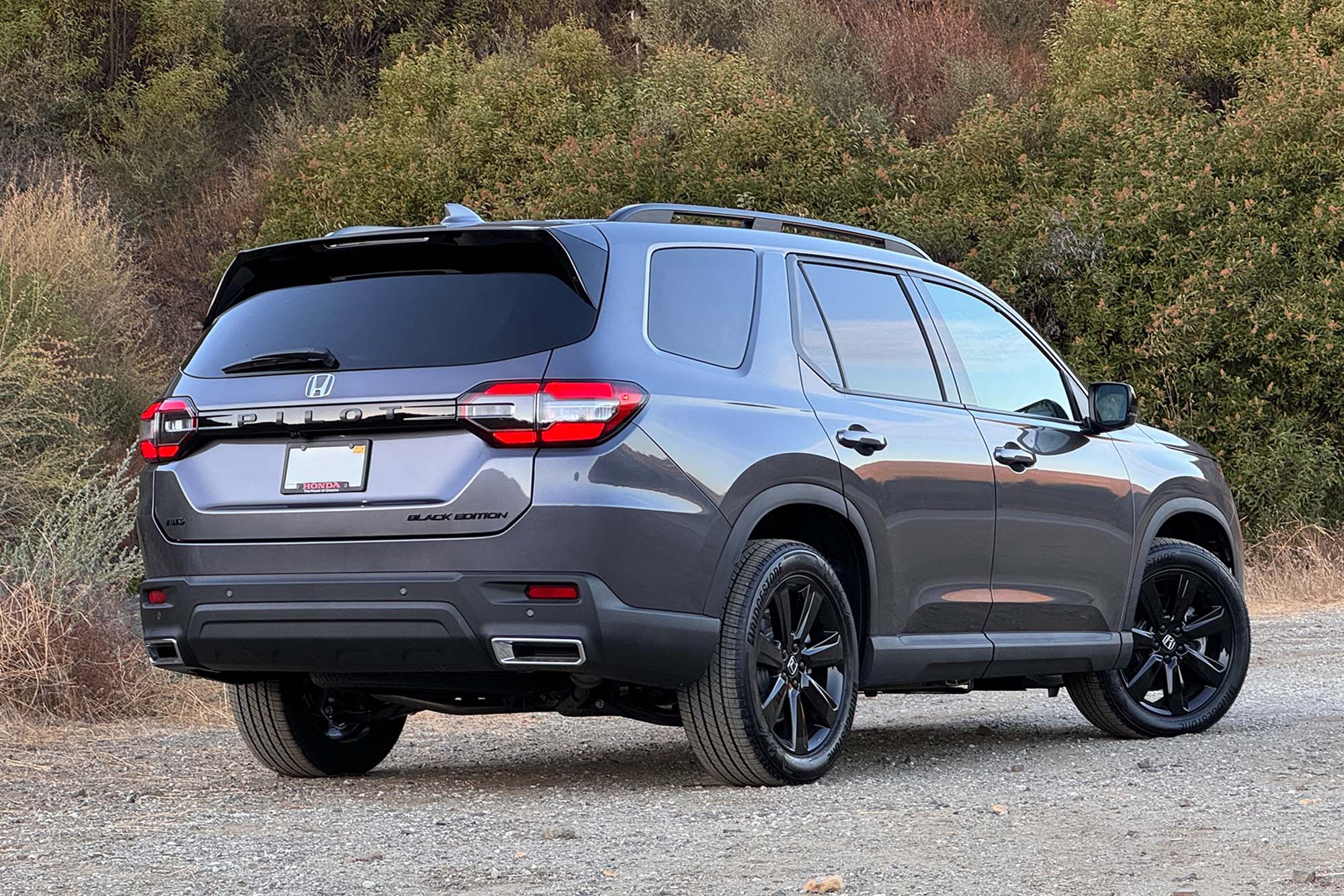 2025 Honda Pilot Black Edition in Modern Steel with a brush-covered hill in the background.