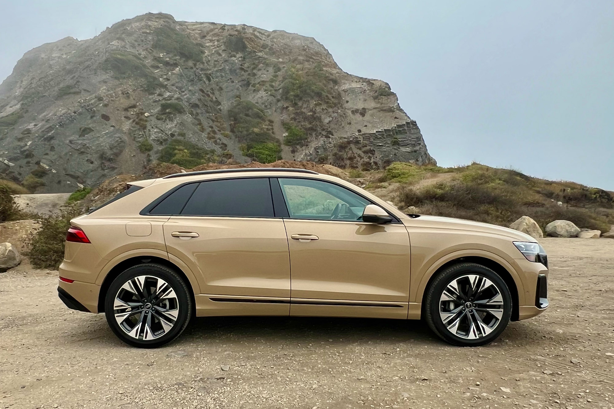 2025 Audi Q8 Prestige in Sakhir Gold Metallic with a rock formation in the background.