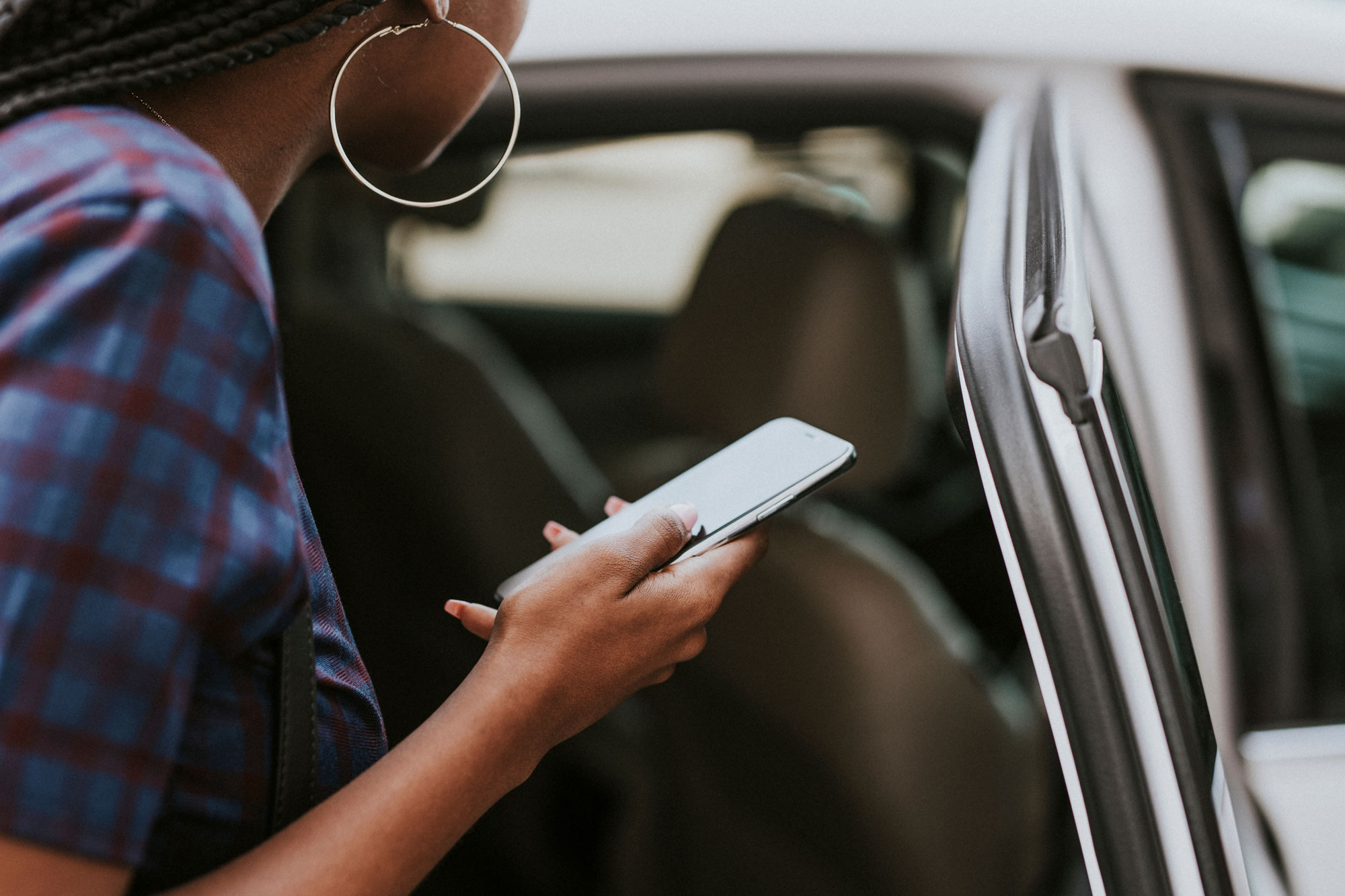 Person looks at phone and inside of a car