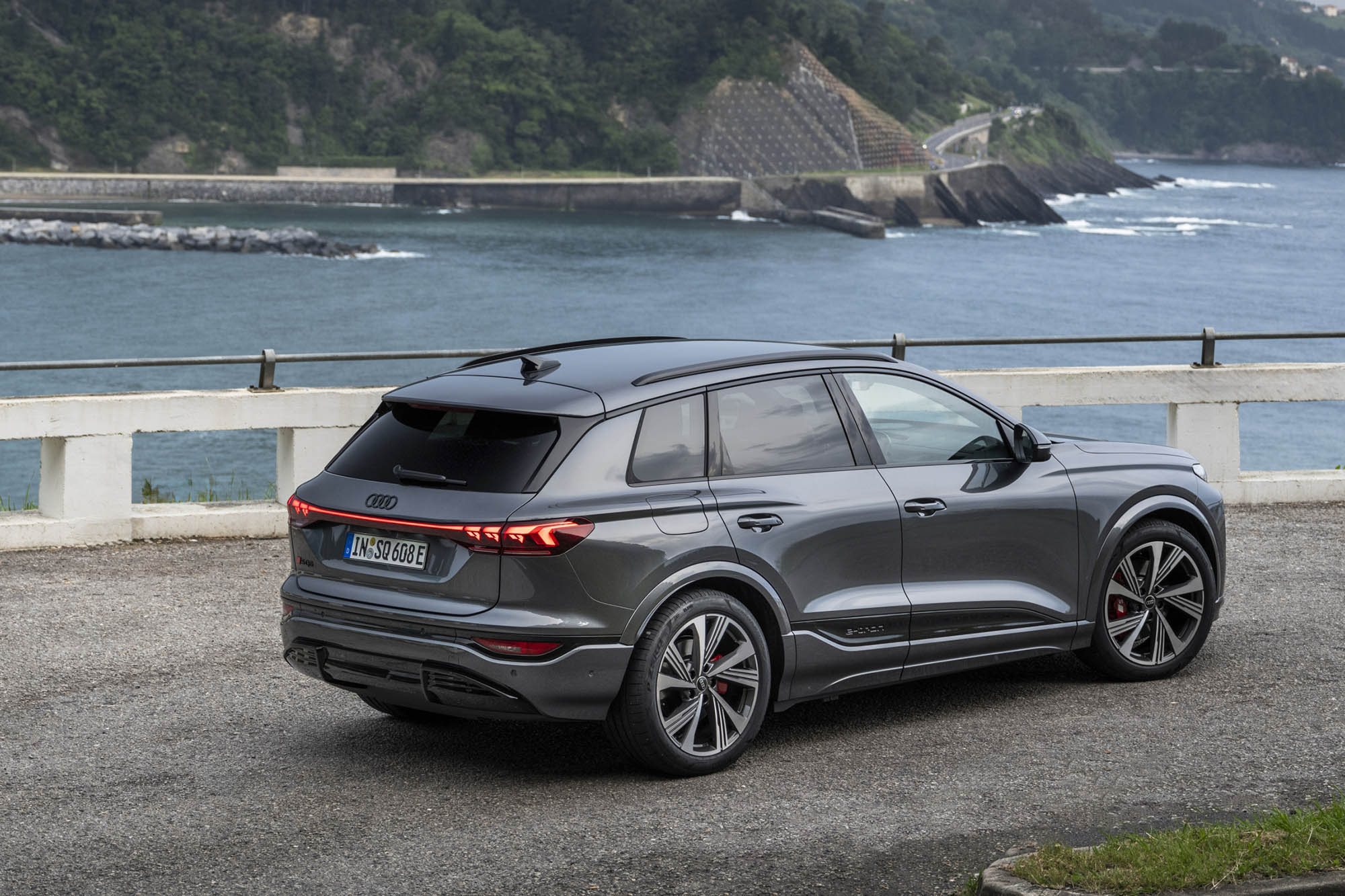 Right-rear view of a 2025 Audi Q6 e-tron on a coastline.