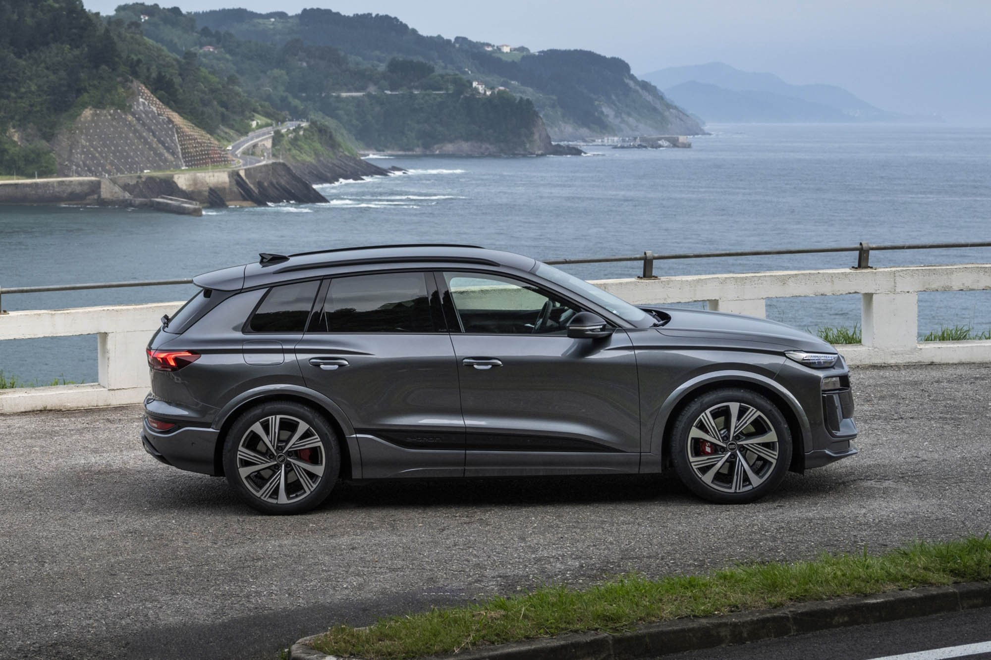 Side view of a gray 2025 Audi Q6 e-tron parked on a coastline.