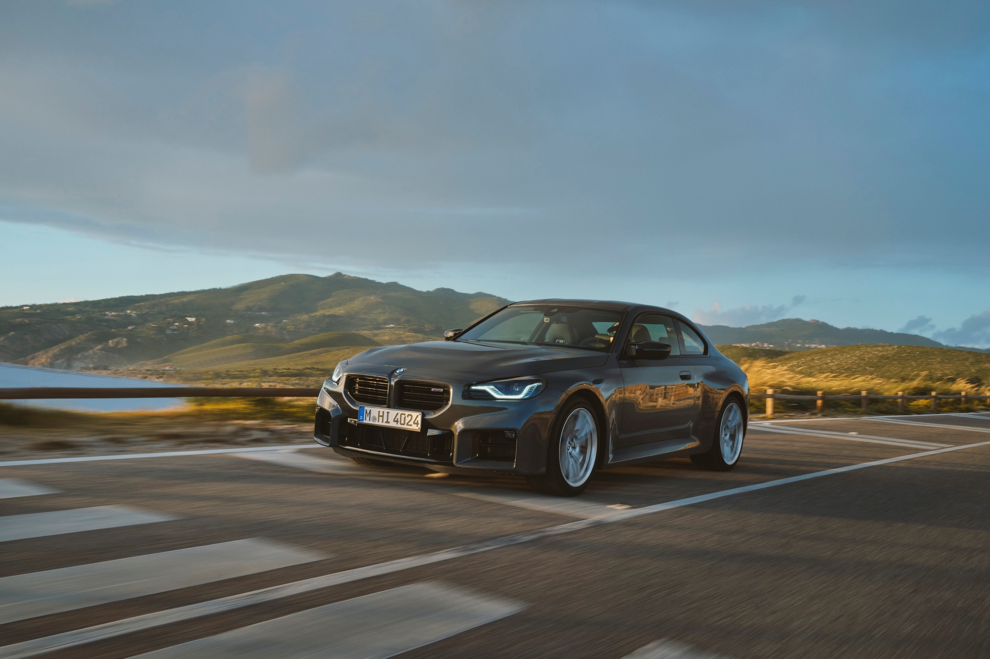 2025 BMW M2 in gray driving alongside a bay