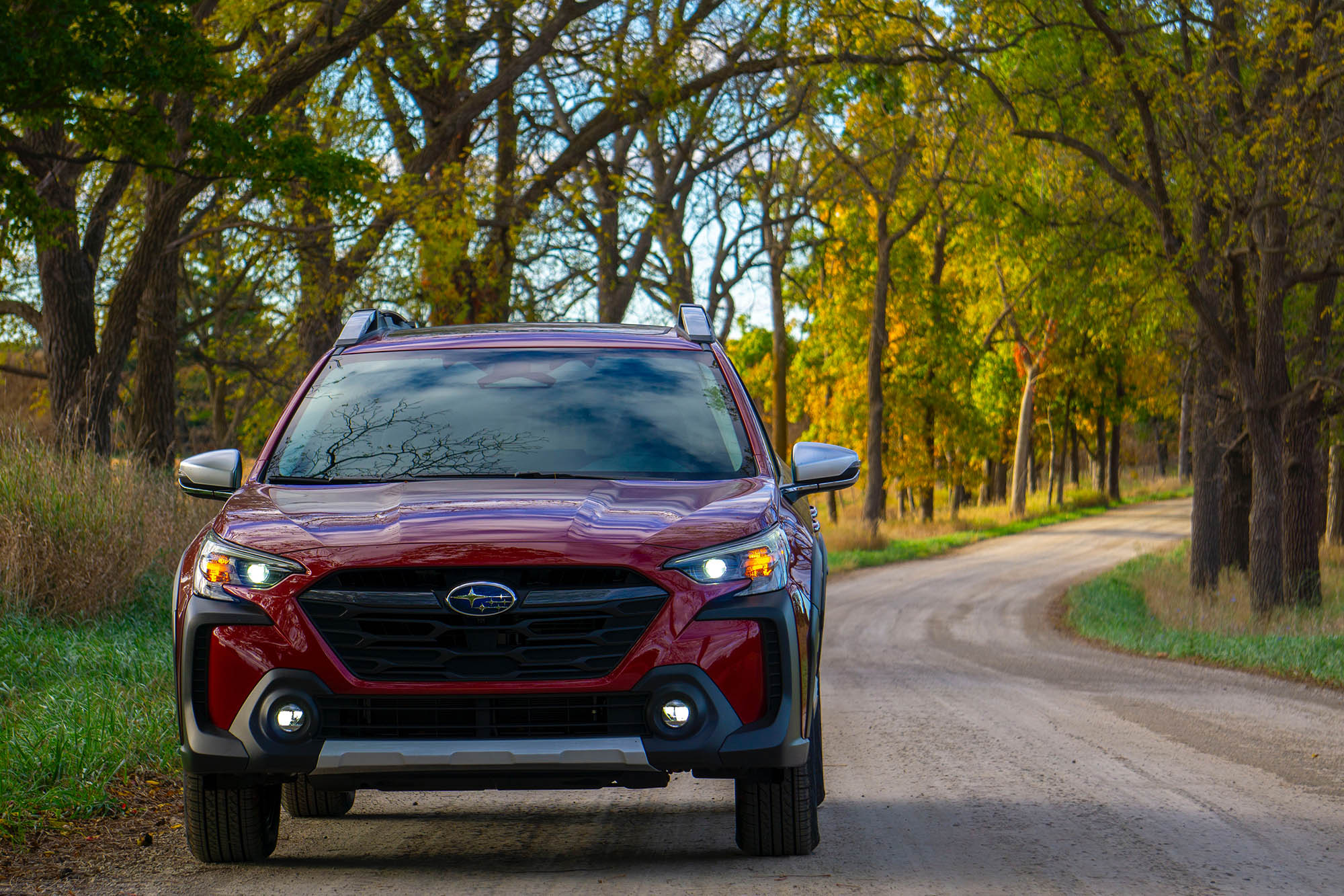 2025 Subaru Outback Touring XT in Crimson Red Pearl, front, with background trees showing fall colors