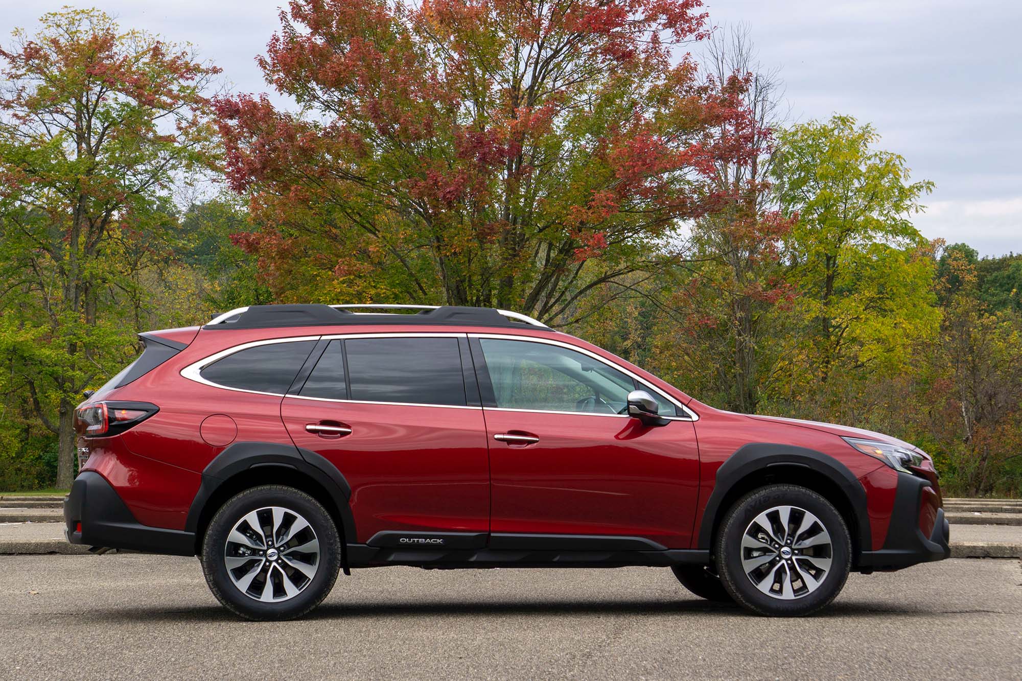 2025 Subaru Outback Touring XT in Crimson Red Pearl, side profile, with background trees showing fall colors