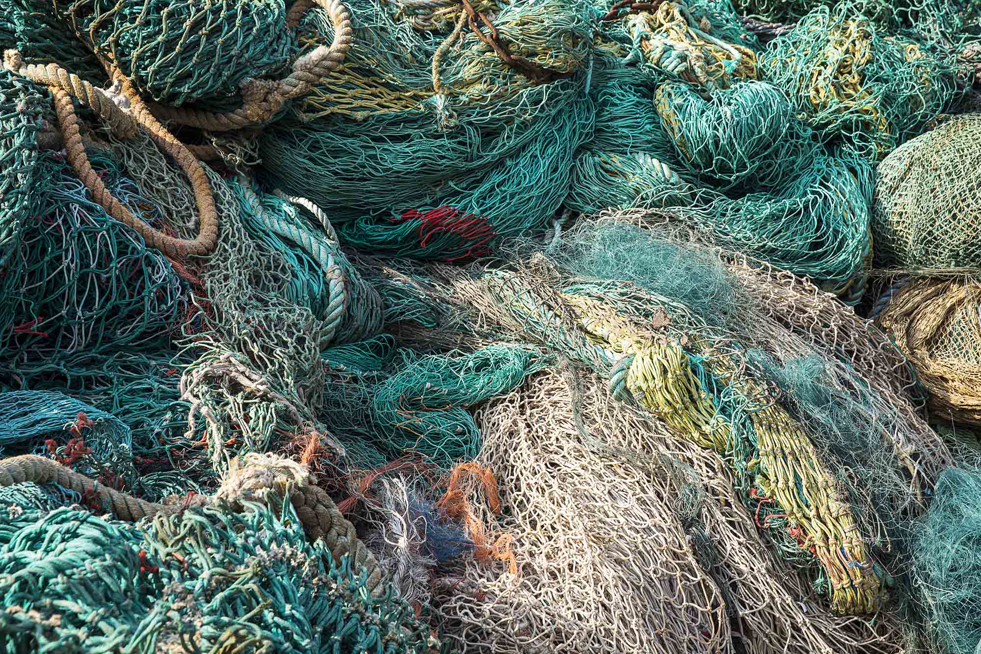 A pile of fishing nets in greens, pinks, and yellows