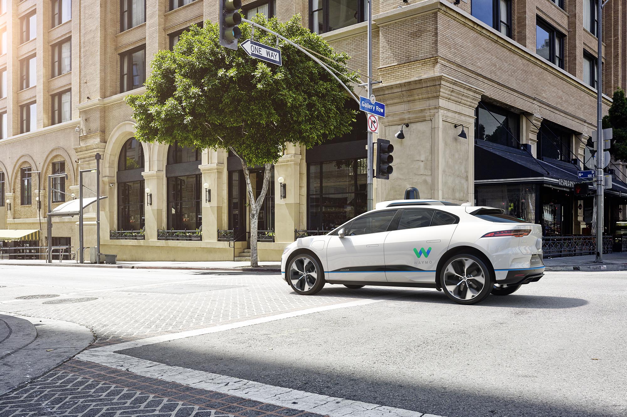 White Jaguar I-Pace being used as a Waymo One robo-taxi drives in downtown Los Angeles.