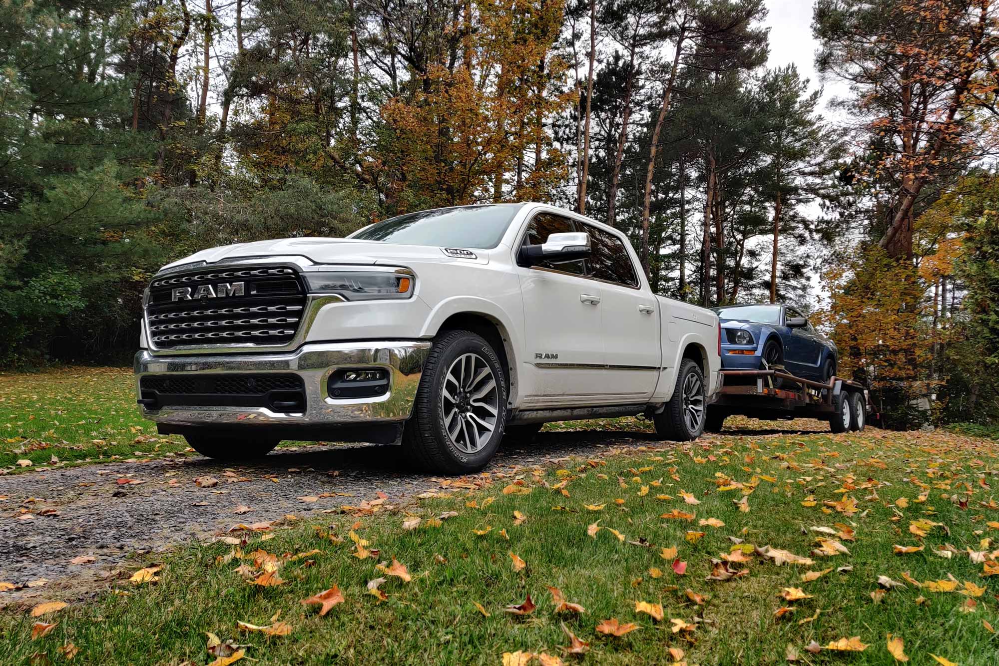 White 2025 Ram 1500 towing a Ford Mustang