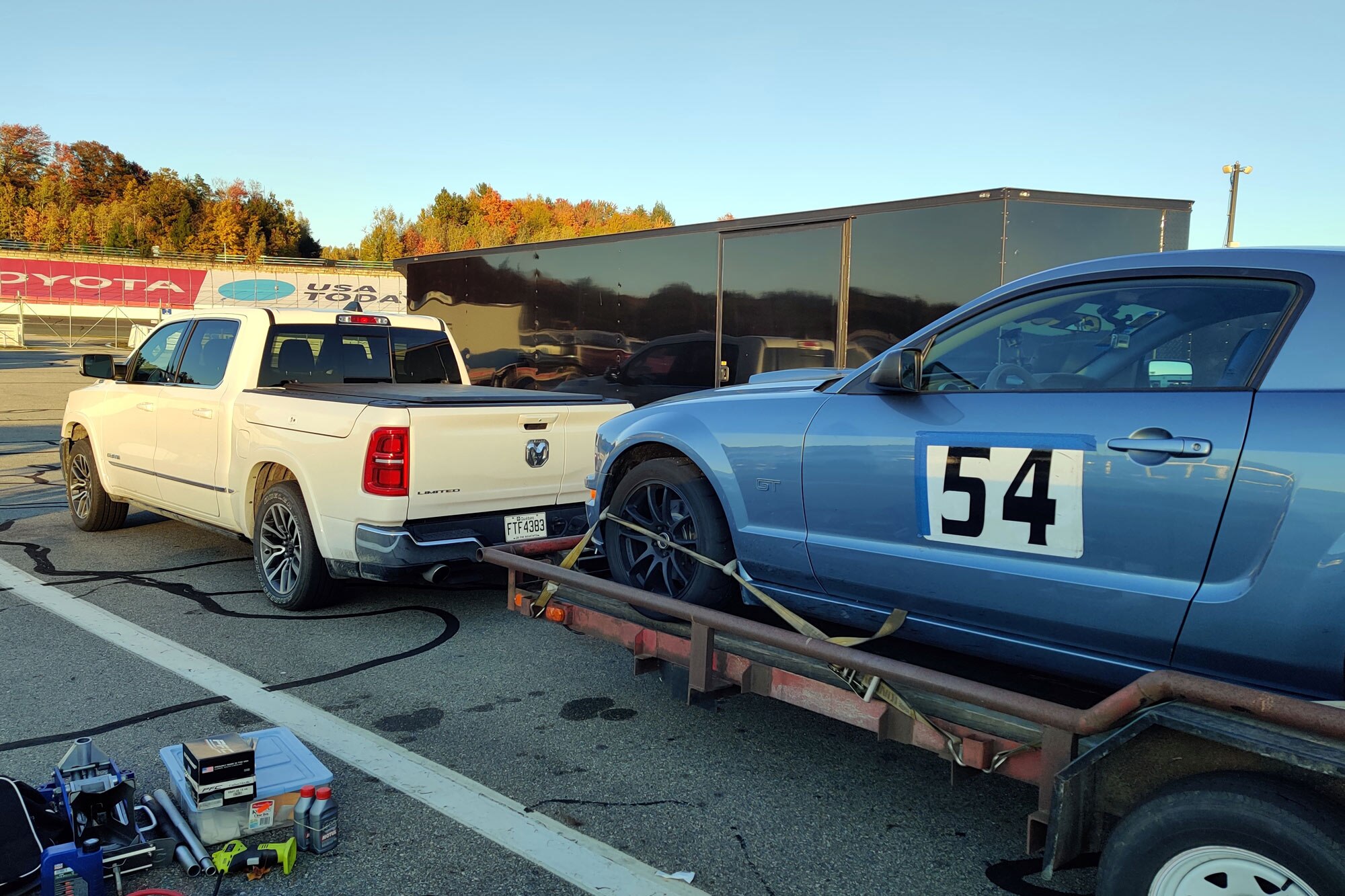 A white 2025 Ram 1500 tows a Ford Mustang