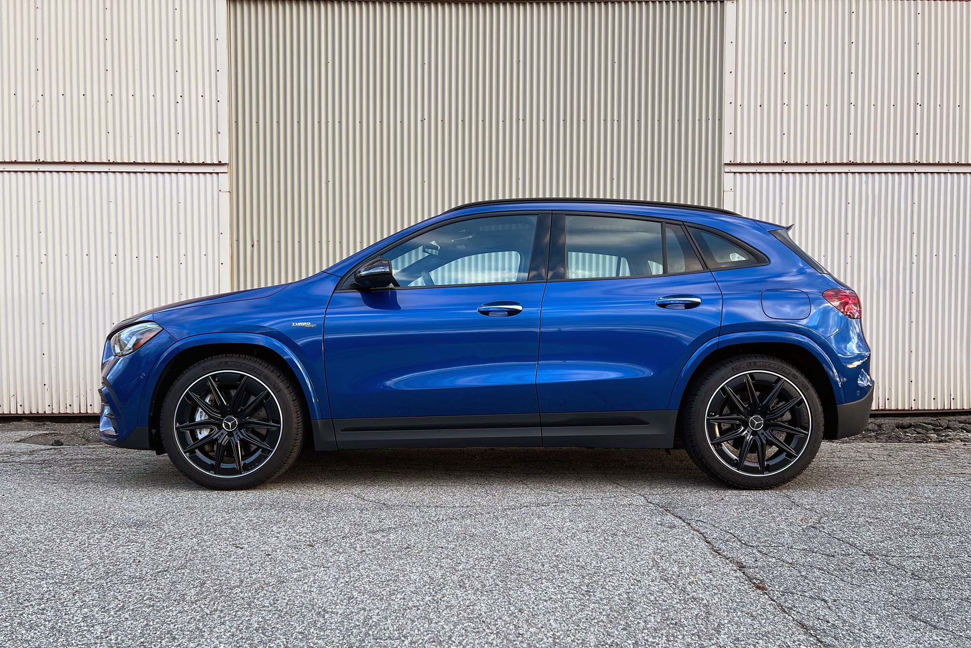 2024 Mercedes-AMG GLA 35 in Starling Blue Metallic parked in front of a warehouse, side view