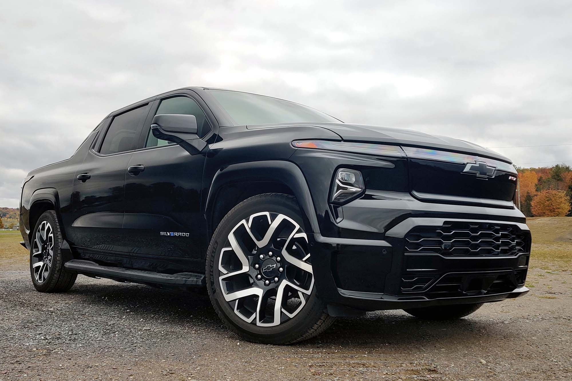 2024 Chevrolet Silverado EV First Edition RST in Black with gray sky and trees with fall color in the background.