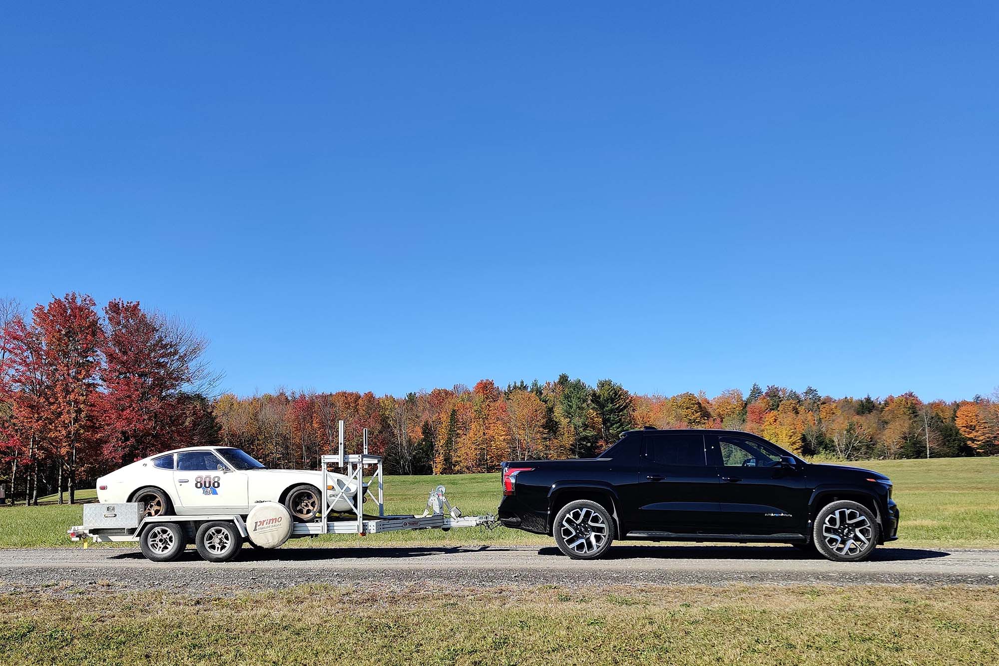 2024 Chevrolet Silverado EV First Edition RST in Black towing a trailer with trees the background.