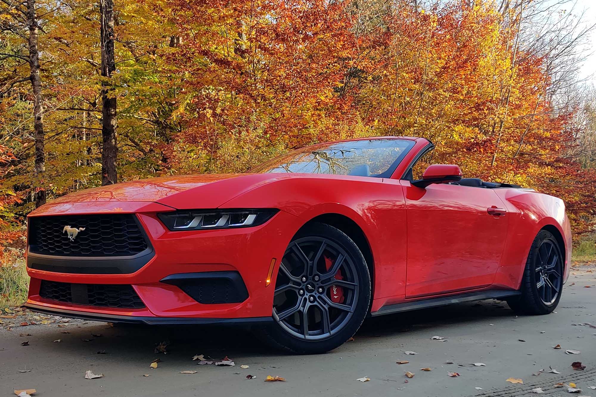 A front view of a red 2024 Ford Mustang Convertible in front of trees.