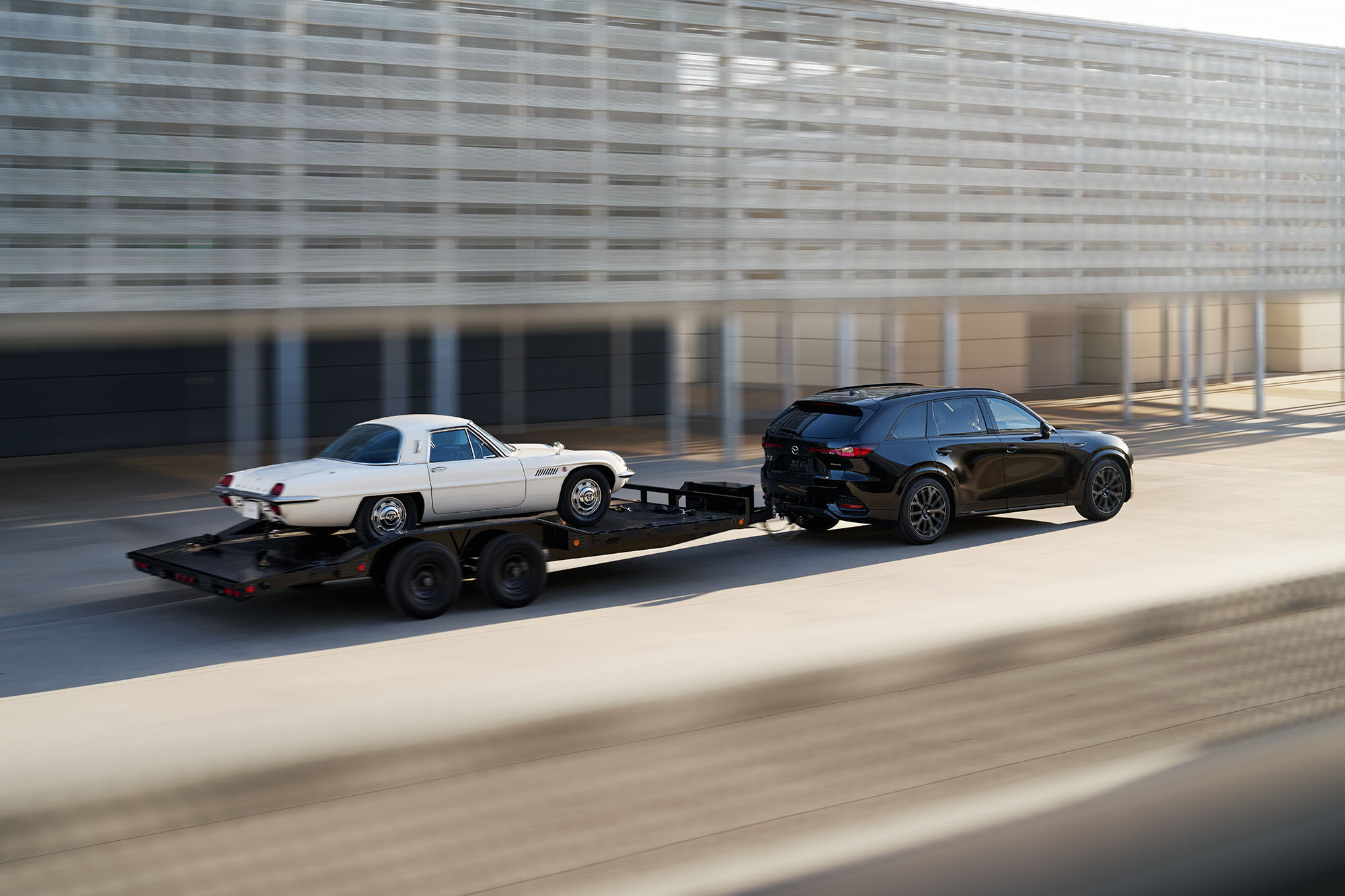 2025 Mazda CX-70 in black towing a car on a trailer