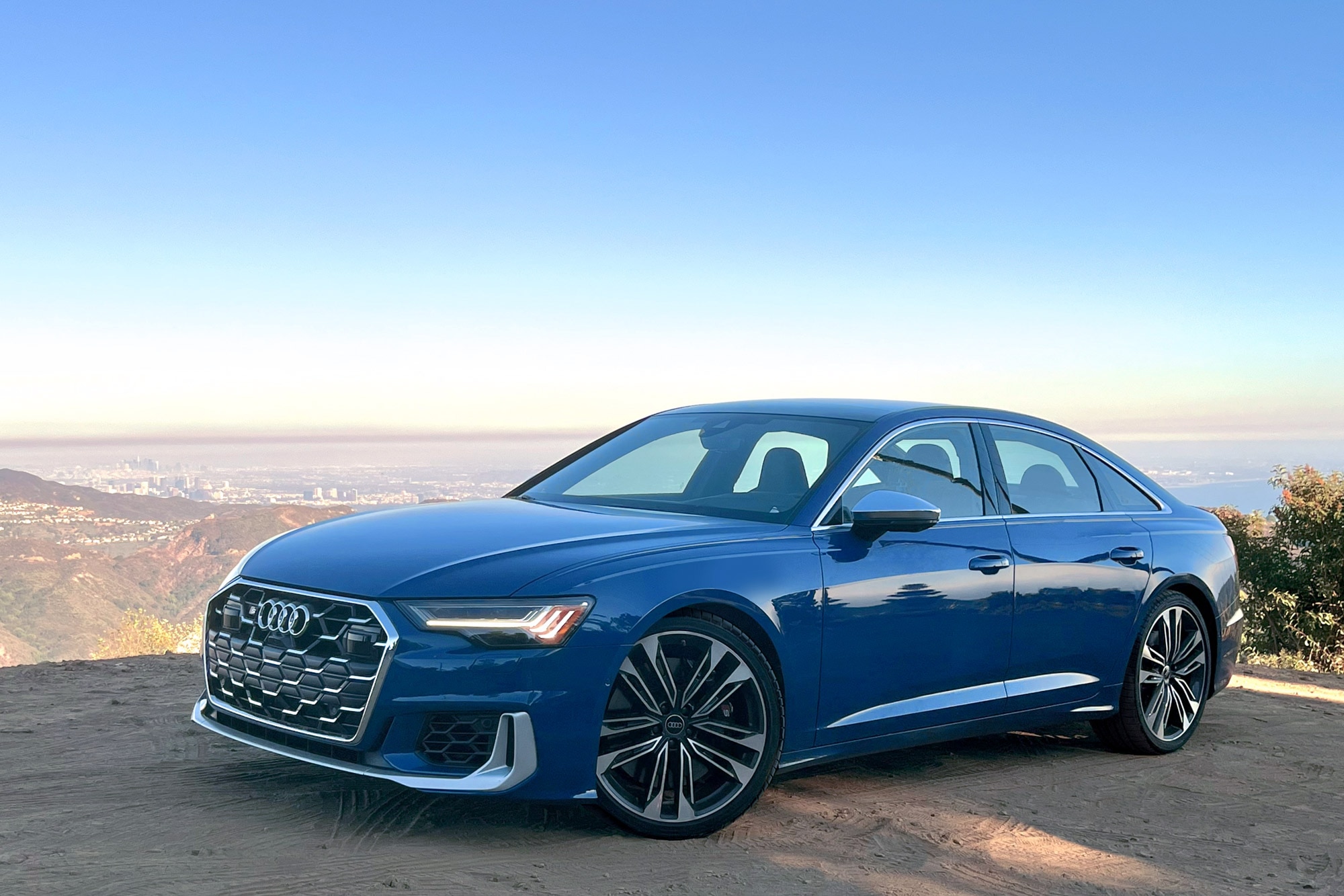 Front quarter 2025 Audi S6 in Ascari Blue with mountains and blue sky in the background