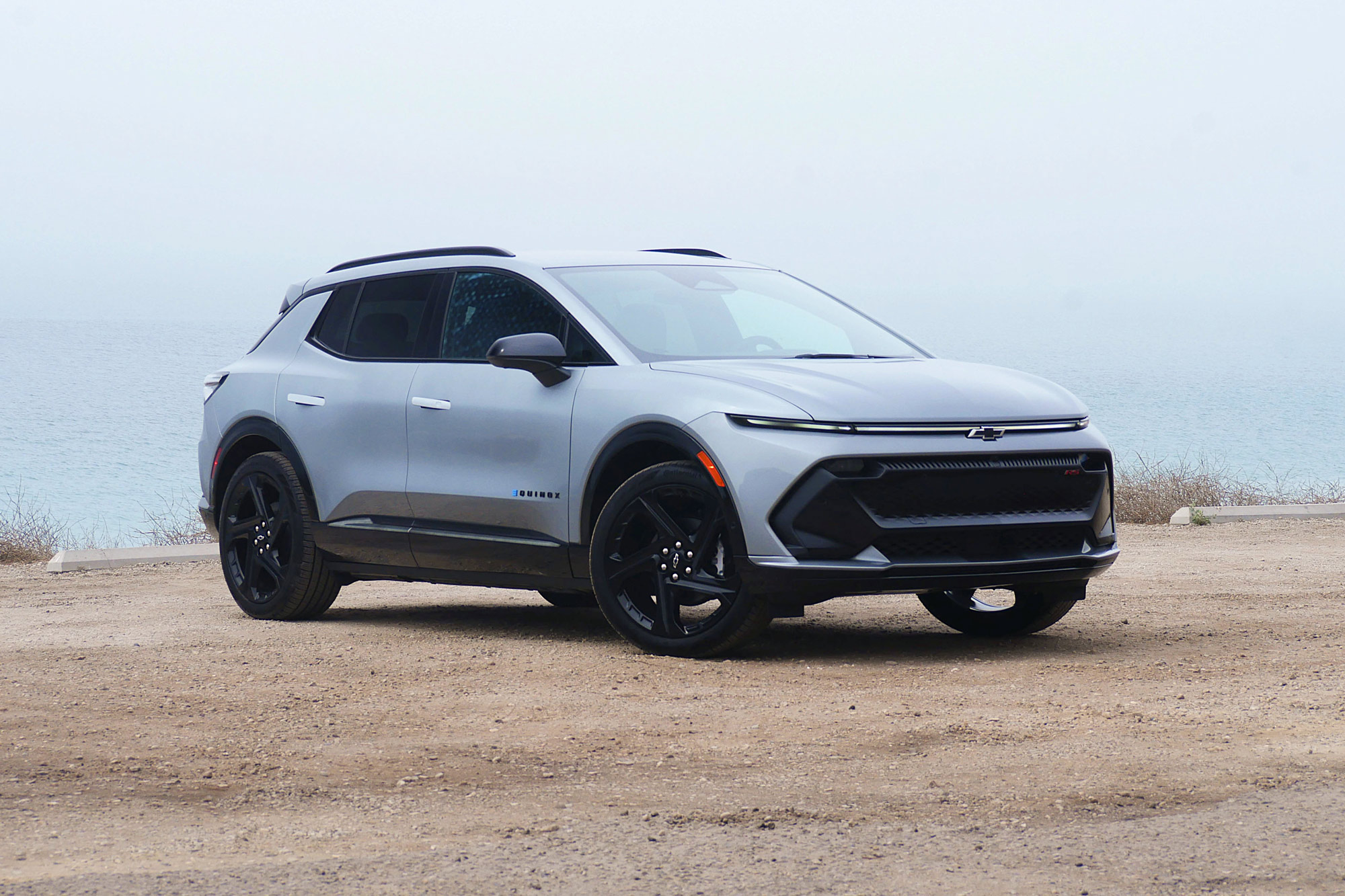 Front quarter 2024 Chevrolet Equinox EV 3RS in Sterling Gray with the foggy Pacific Ocean in the background