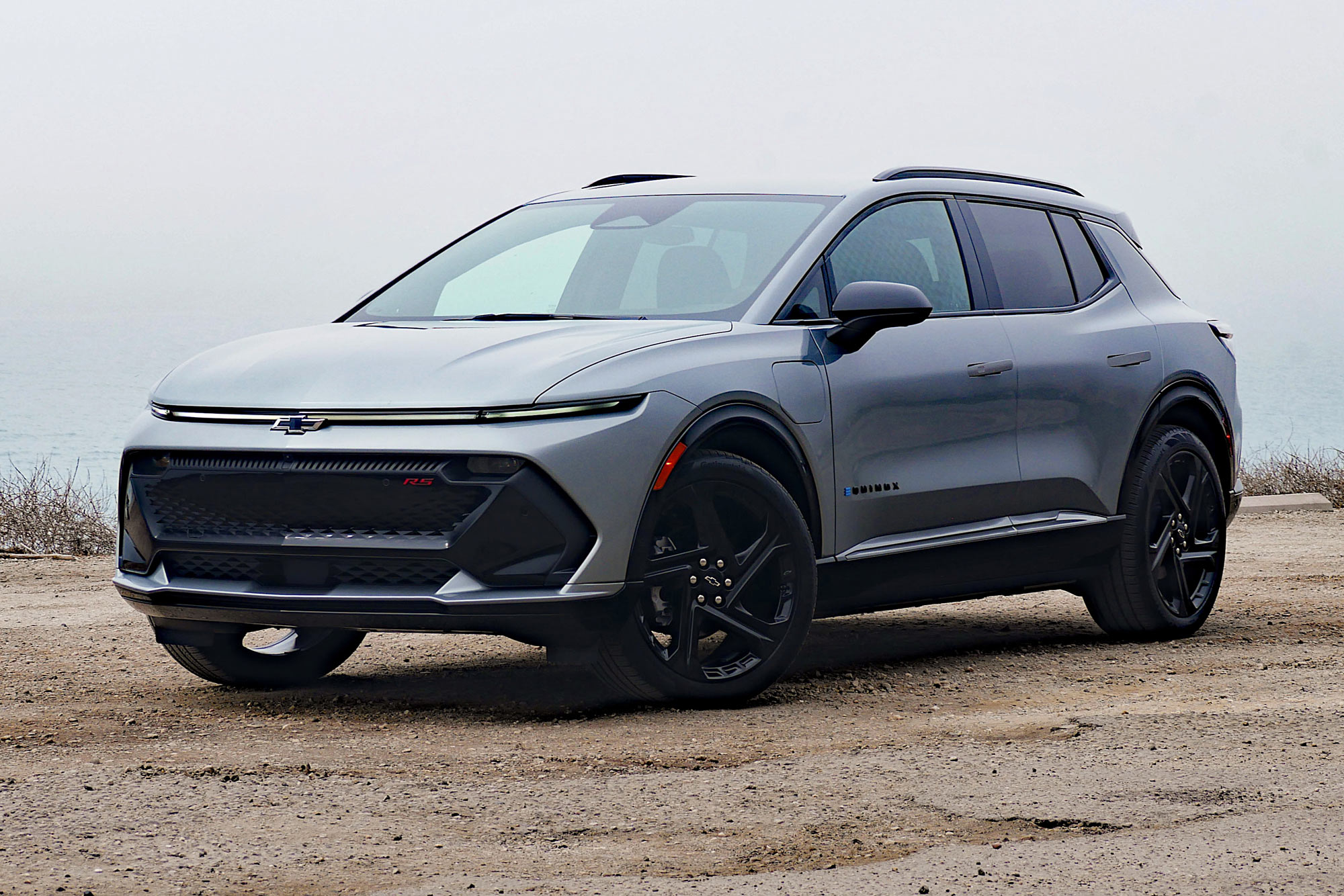 Front quarter 2024 Chevrolet Equinox EV 3RS in Sterling Gray with the foggy Pacific Ocean in the background