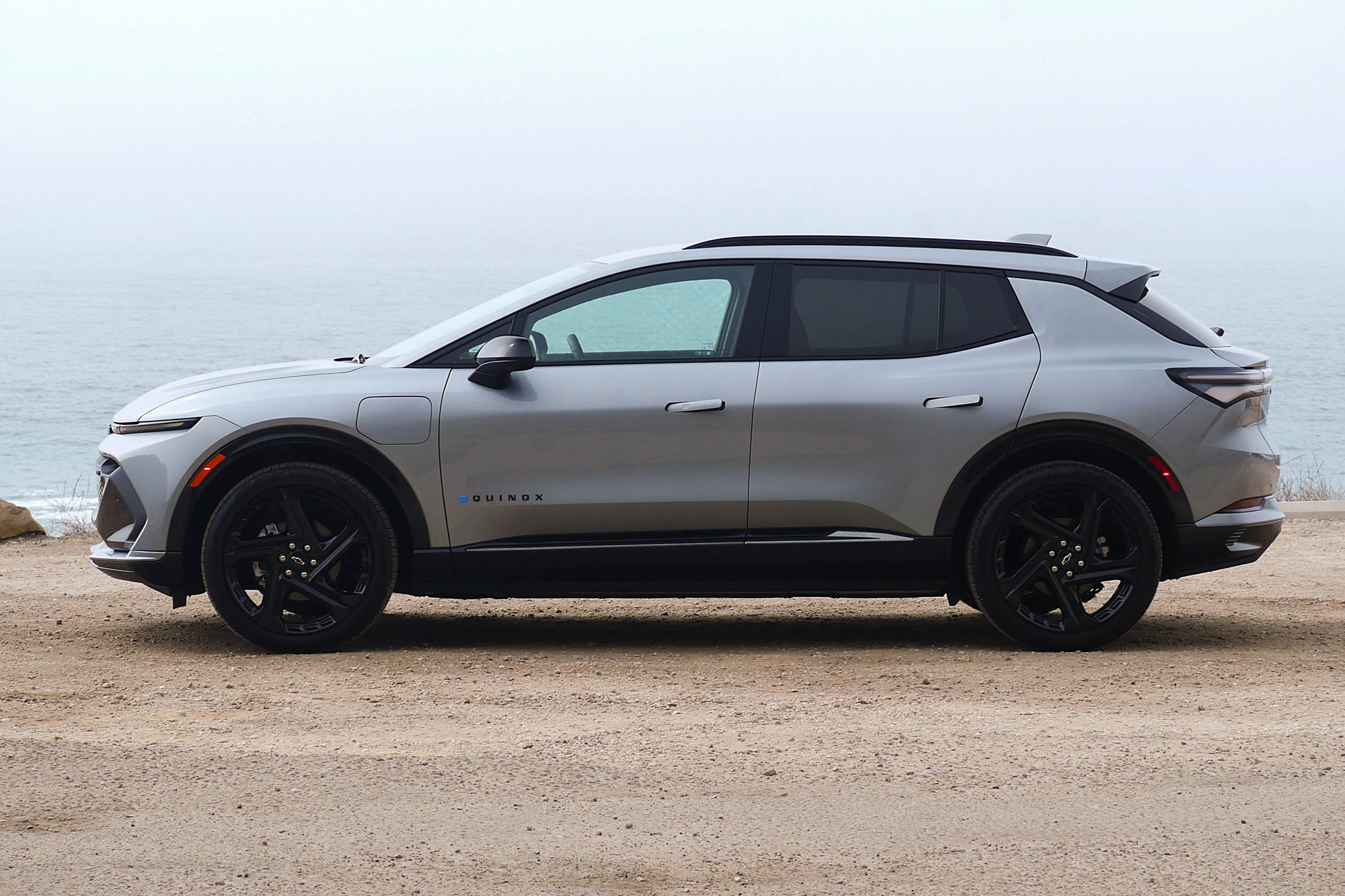 Side 2024 Chevrolet Equinox EV 3RS in Sterling Gray with the foggy Pacific Ocean in the background