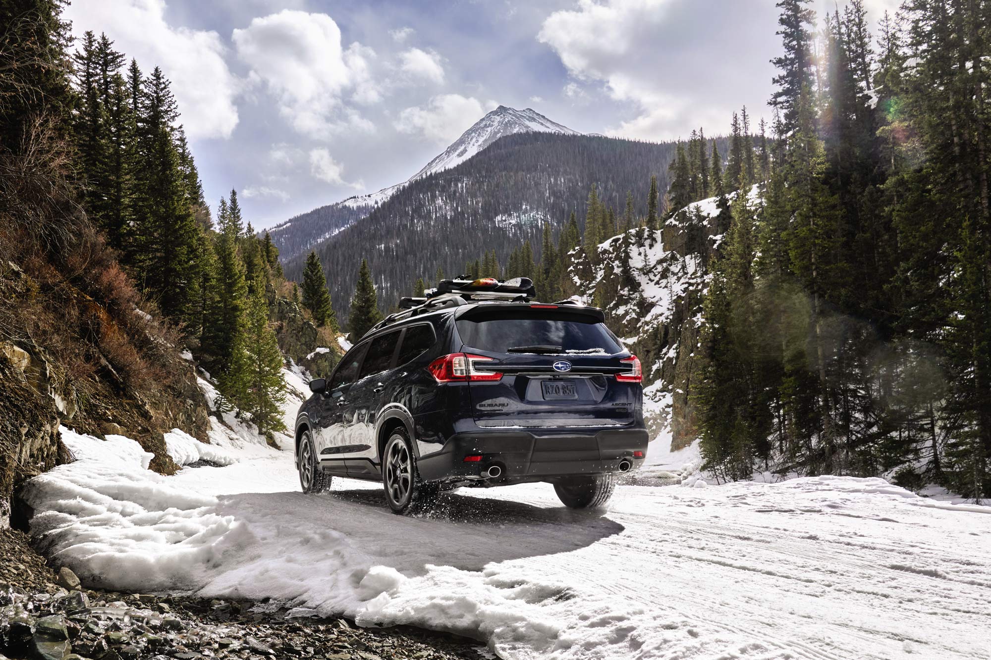 Blue 2024 Subaru Ascent driving through the snowy mountains