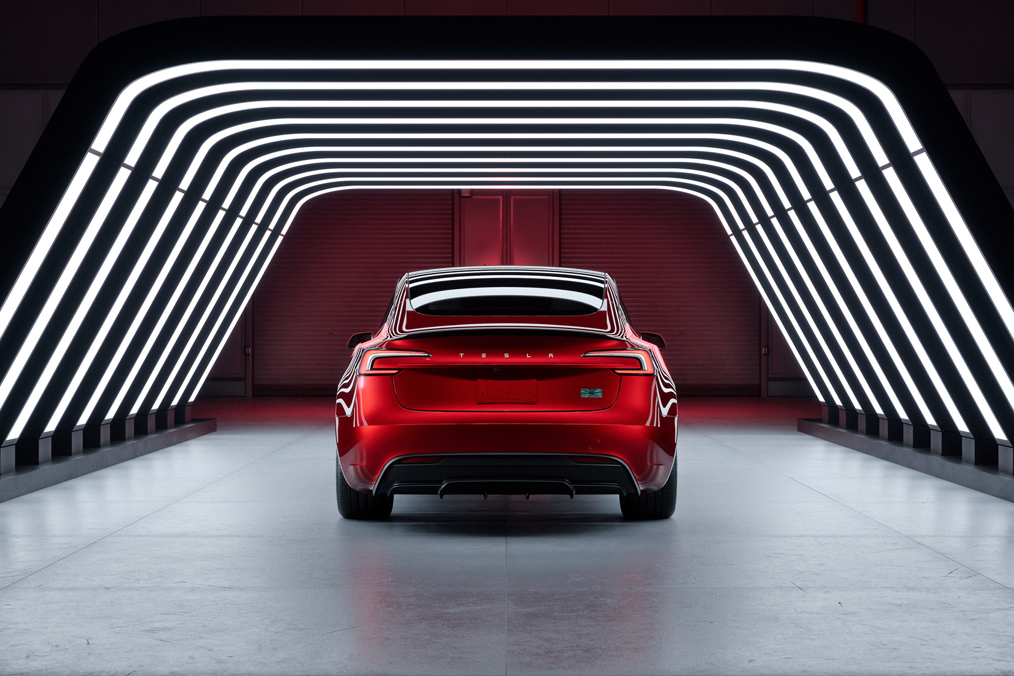 2025 Tesla Model 3 Performance in Ultra Red under an archway of light rear