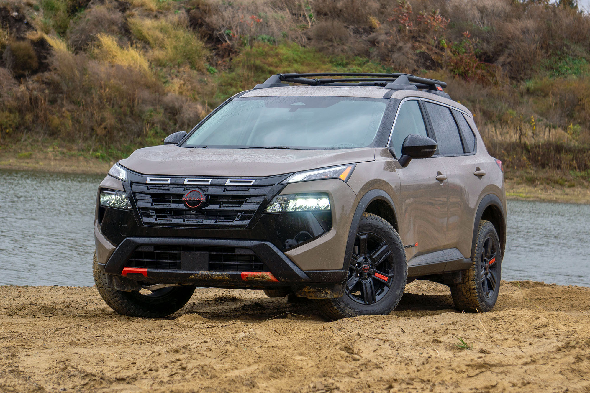 2025 Nissan Rogue Rock Creek in Baja Storm Metallic parked in front of a stream.