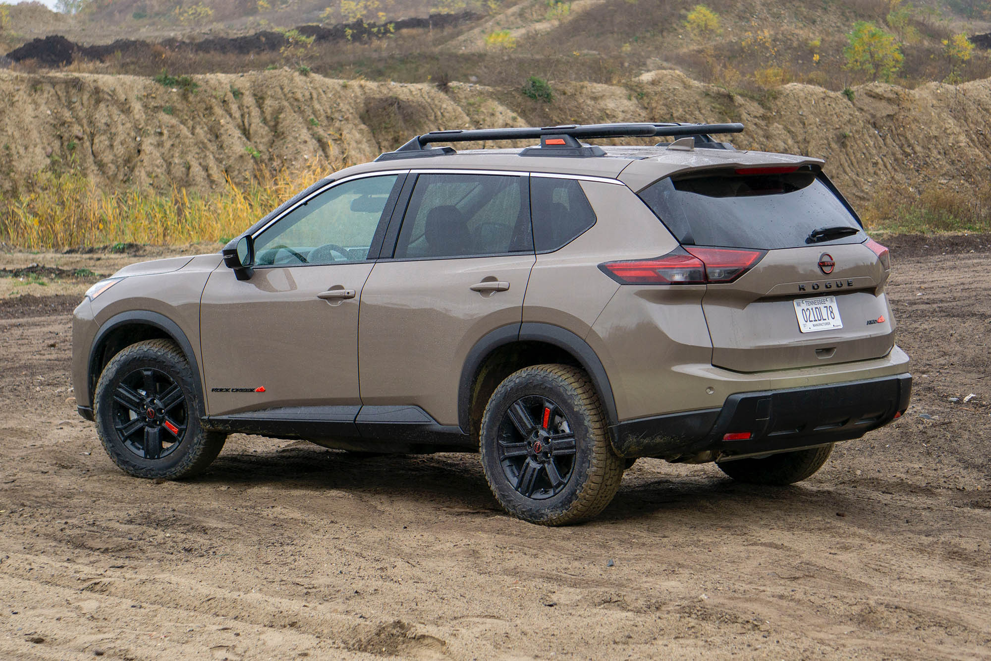 2025 Nissan Rogue Rock Creek in Baja Storm Metallic parked on dirt, rear