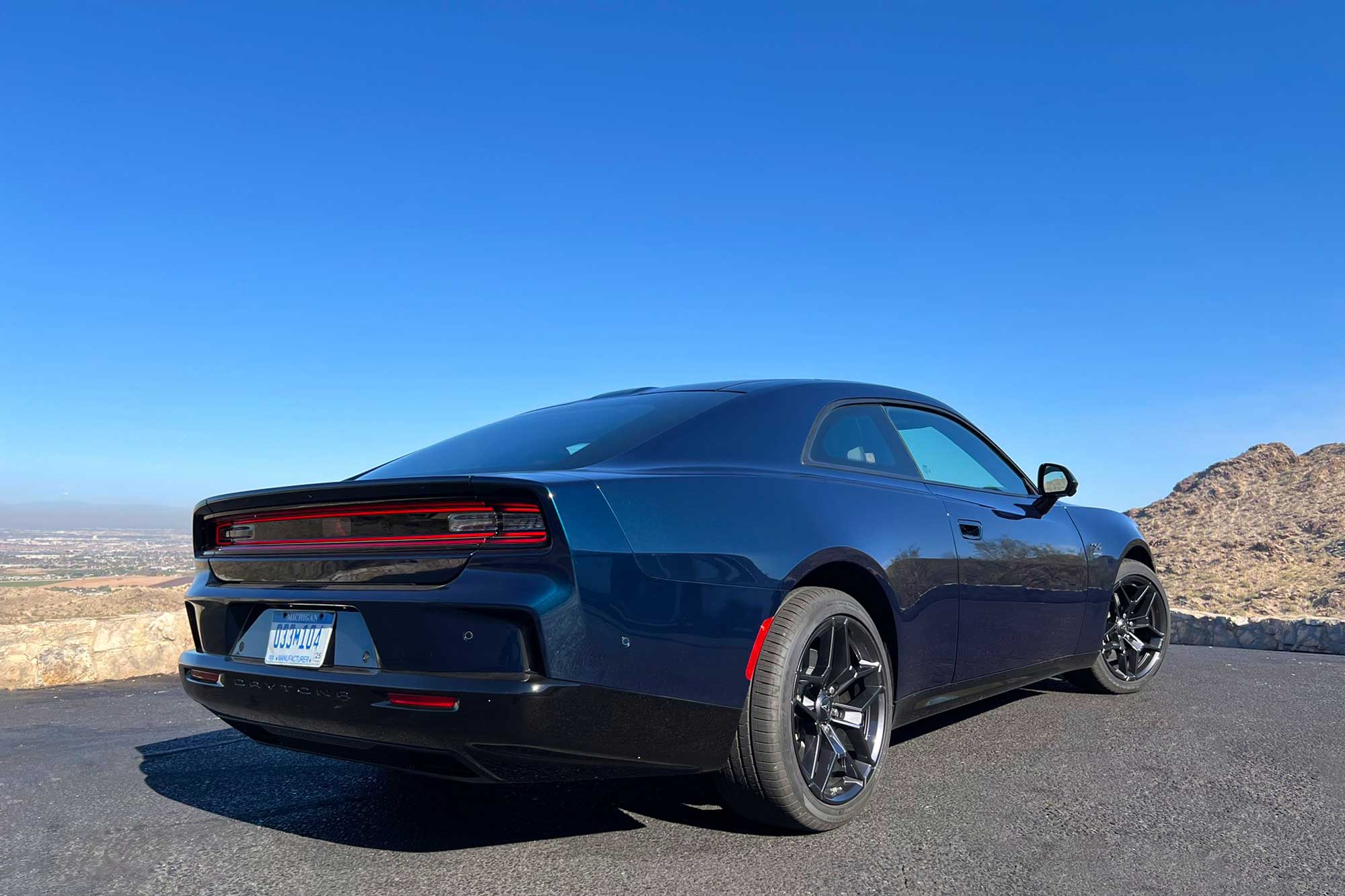 2024 Dodge Charger Daytona R/T in After Dark, rear, with the desert and blue skies in the background.