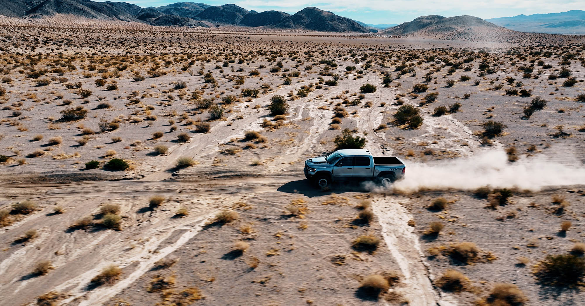 2025 Ram 1500 RHO in Billet Silver Metallic driving on a dusty trail in Johnson Valley, California