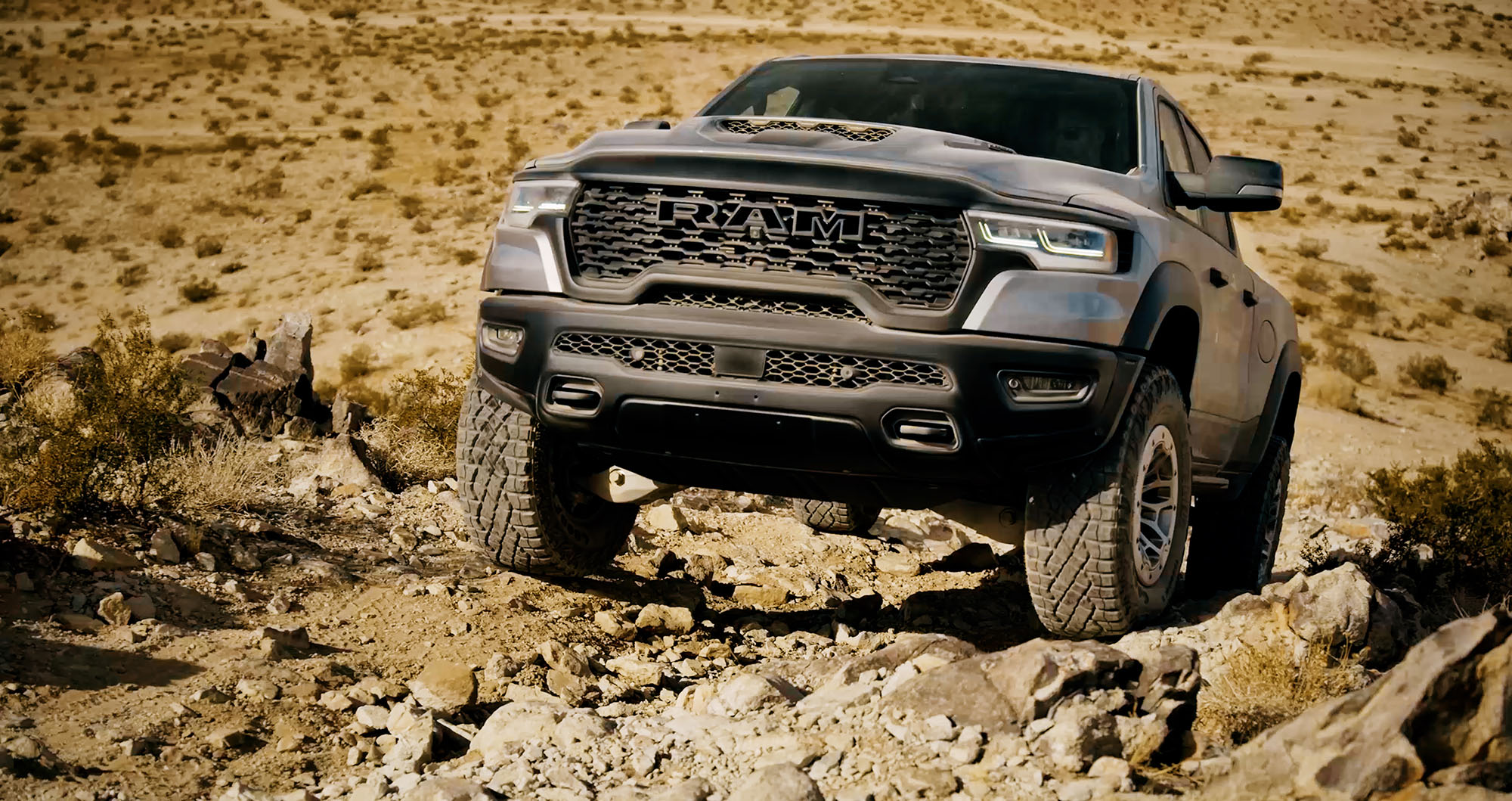 2025 Ram 1500 RHO in Billet Silver Metallic climbing a rocky hill in Johnson Valley, California