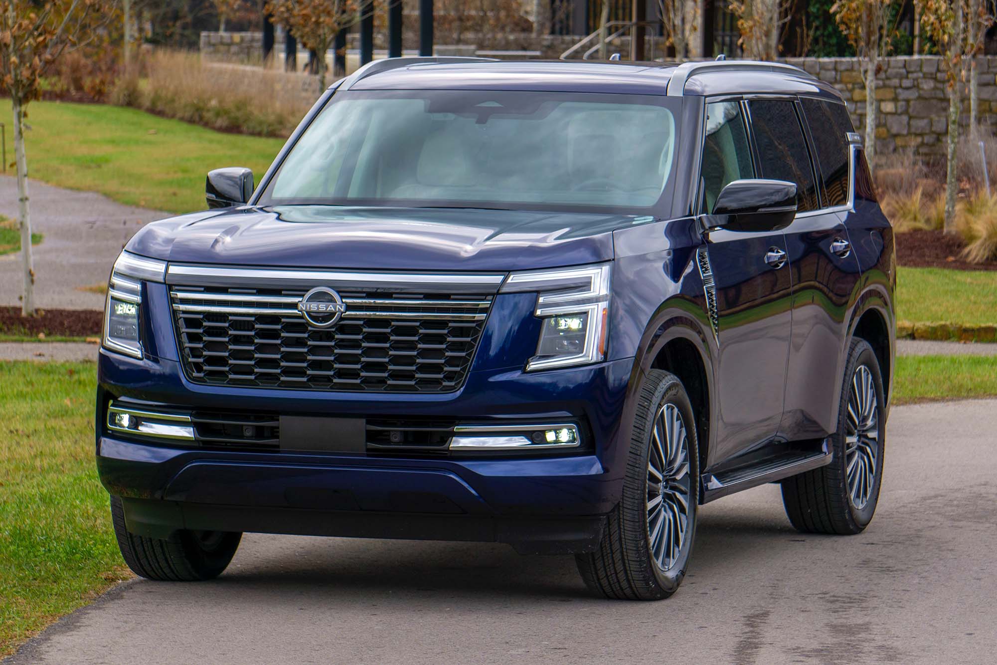 2025 Nissan Armada Platinum Reserve in Ocean Blue Pearl with grass and a lodge in the background.