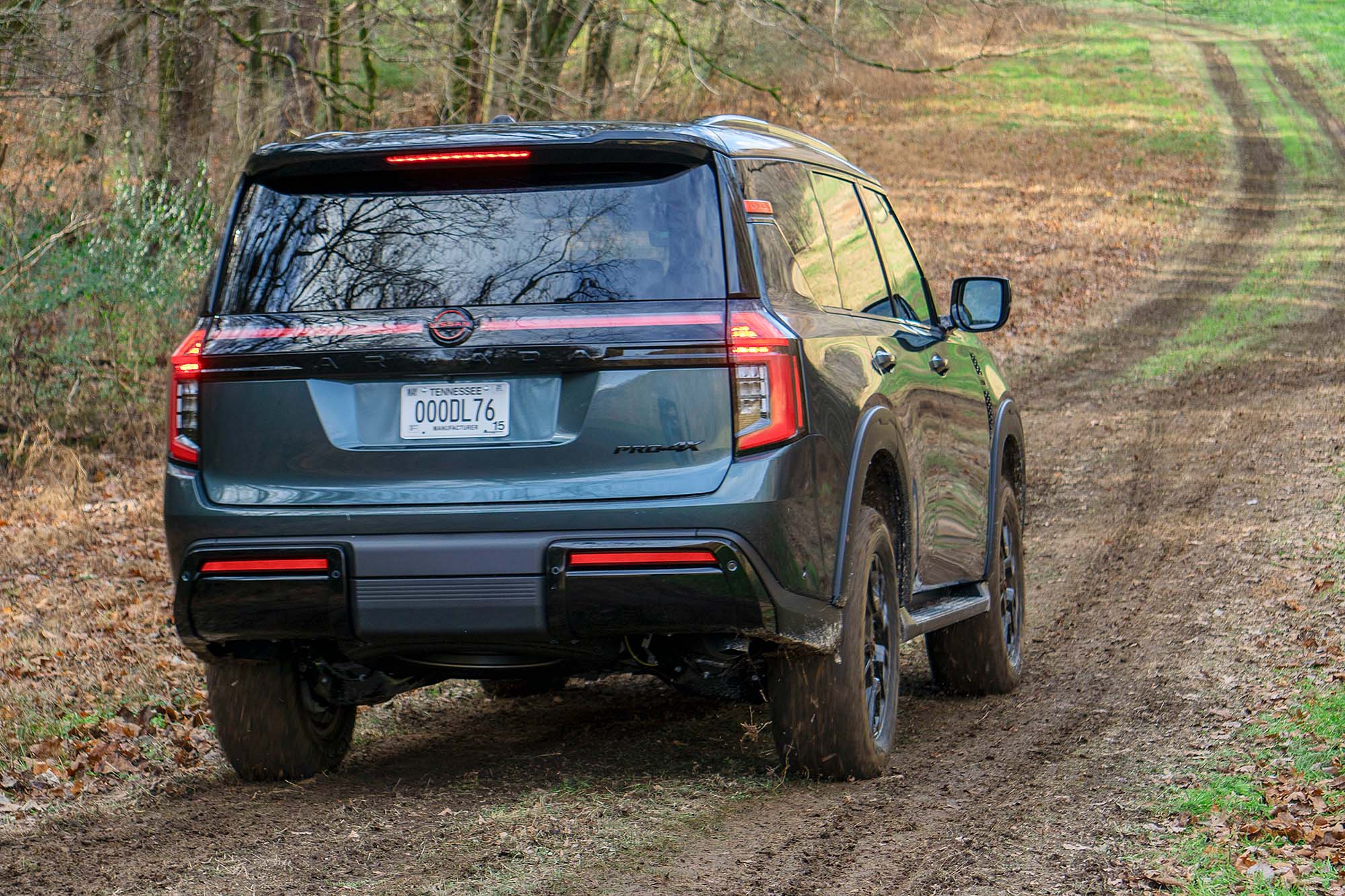 2025 Nissan Armada Pro-4X in Alpine Metallic with a muddy path and trees ahead of it.