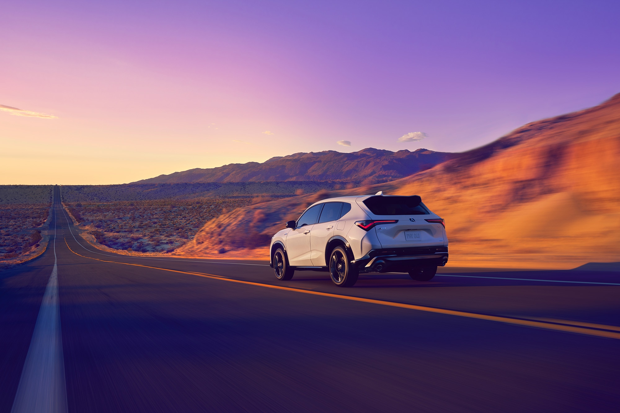 2025 Acura ADX A-Spec in white, driving down desert highway, rear