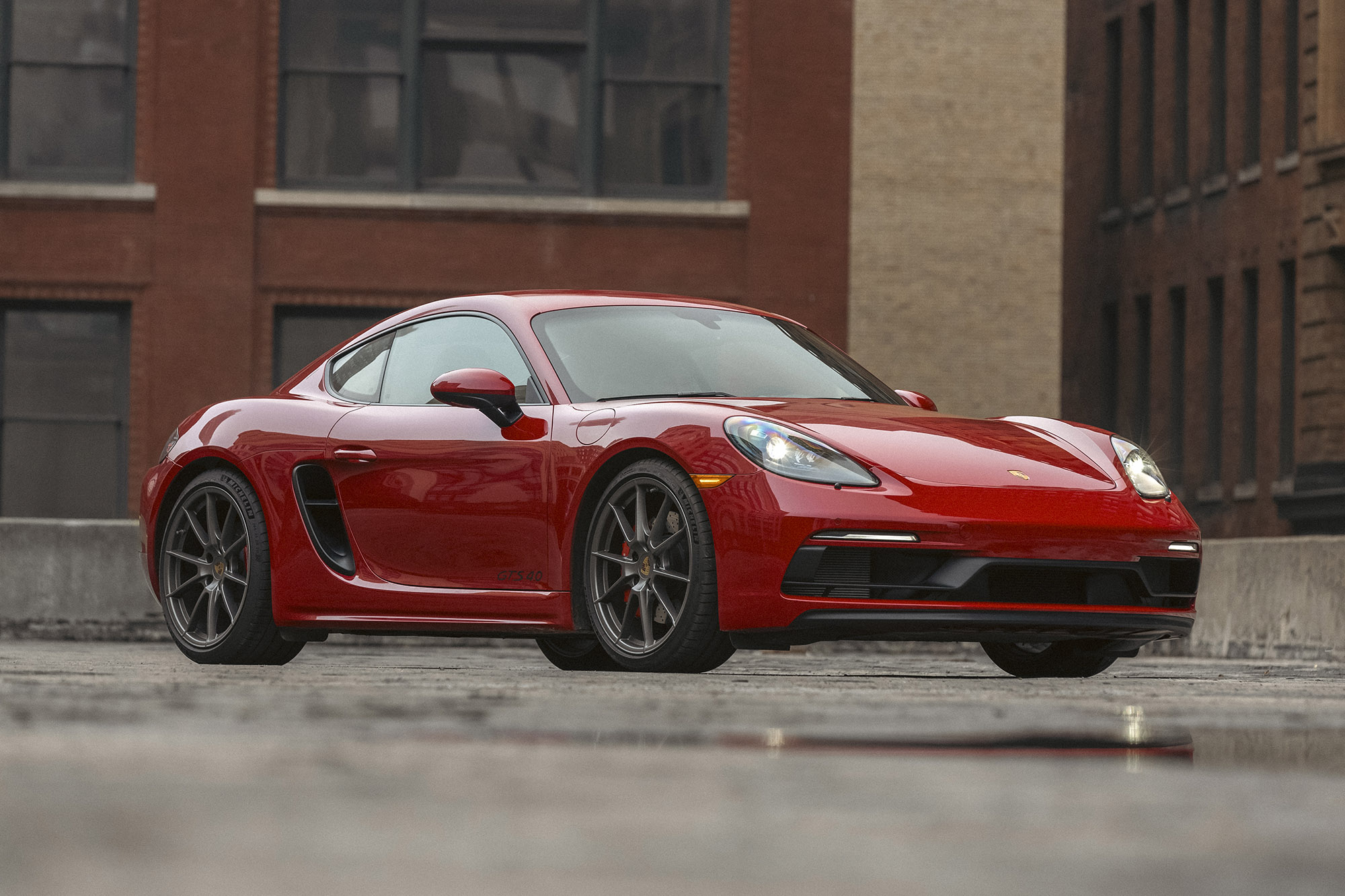 Red Porsche sedan parked on pavement with buildings behind