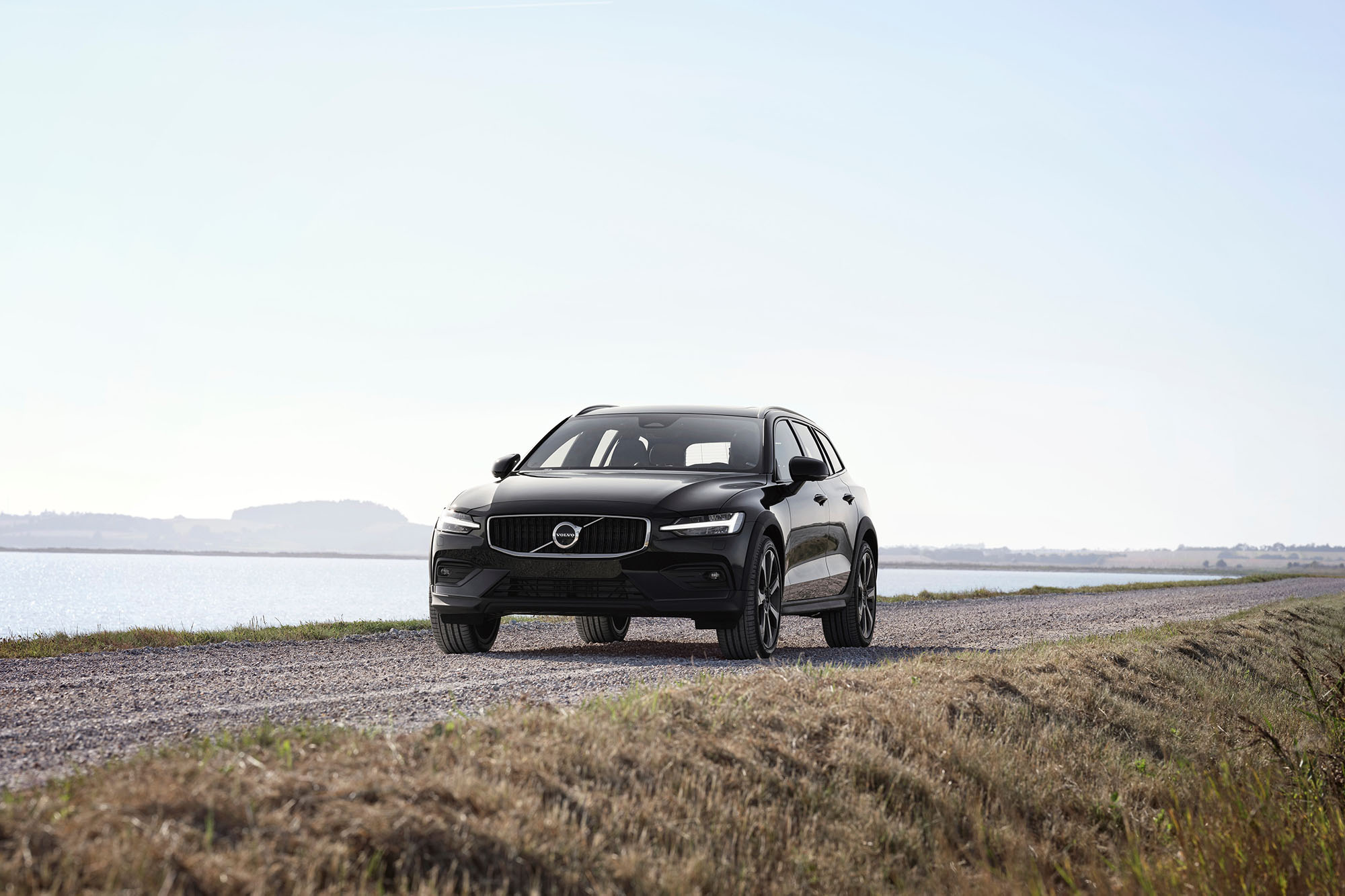 Black Volvo SUV driving next to a body of water