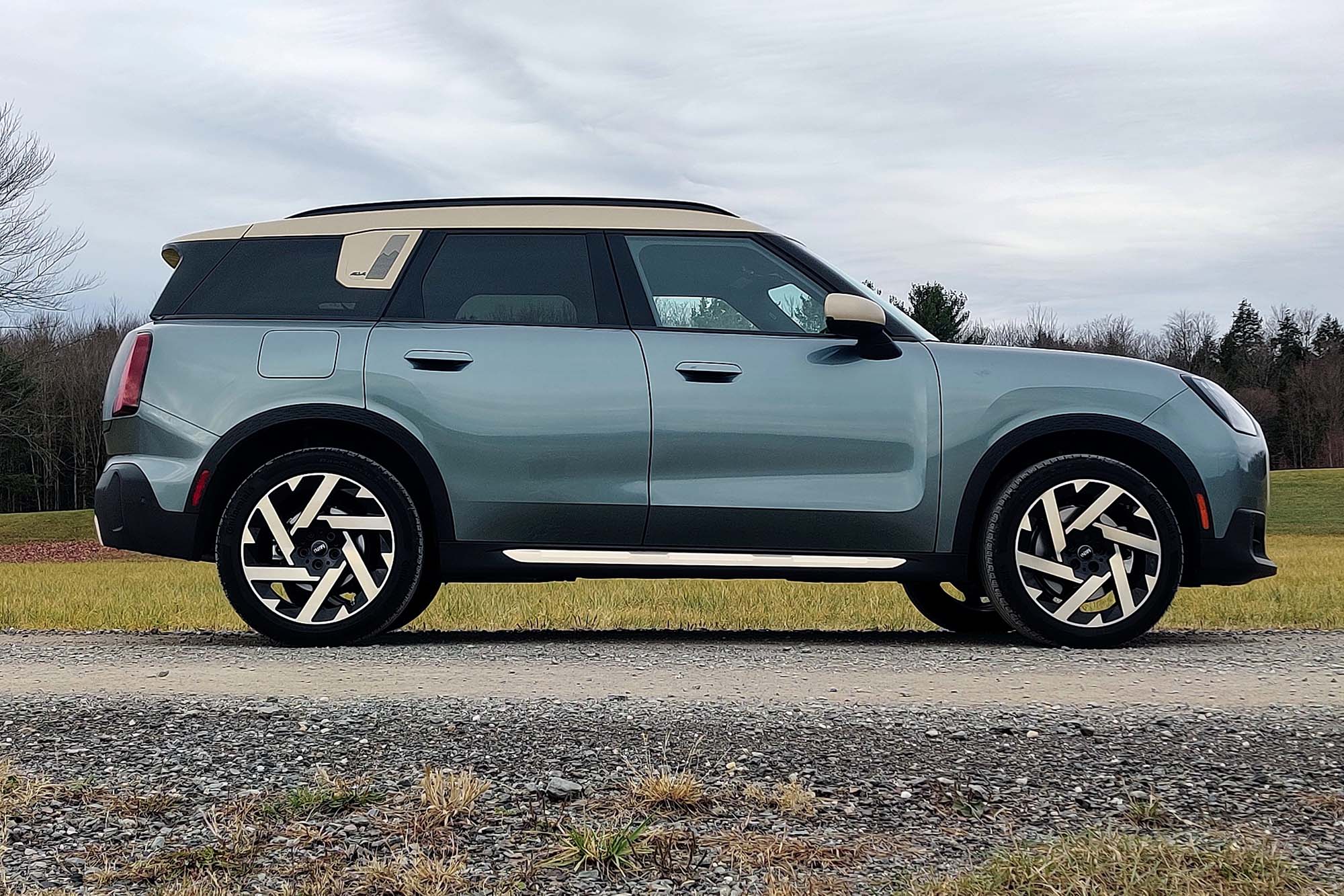 2025 Mini Countryman S All4 in Smokey Green with a field, trees, and gray skies in the background.