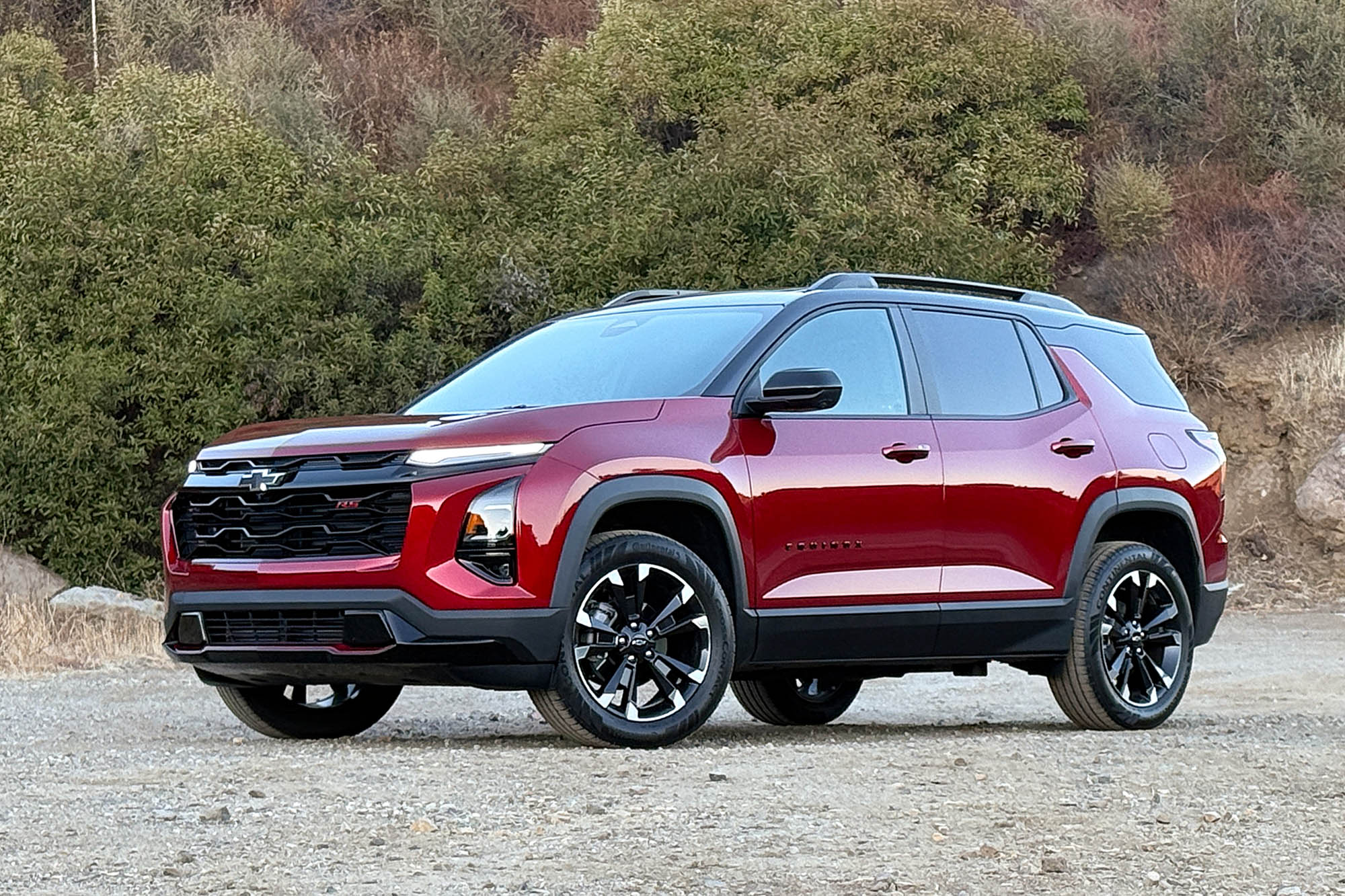 2025 Chevrolet Equinox RS in Radiant Red with a brush-covered hillside in the background.