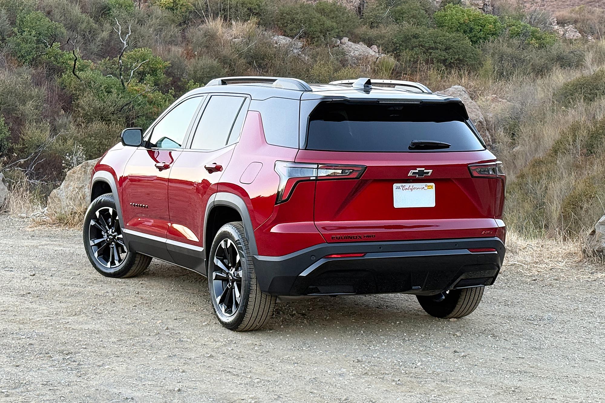 2025 Chevrolet Equinox RS in Radiant Red with a brush-covered hillside in the background.