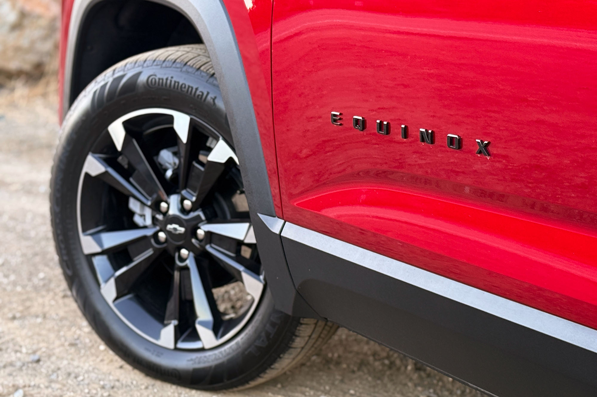 2025 Chevrolet Equinox RS in Radiant Red showing the Equinox badge and front left wheel.